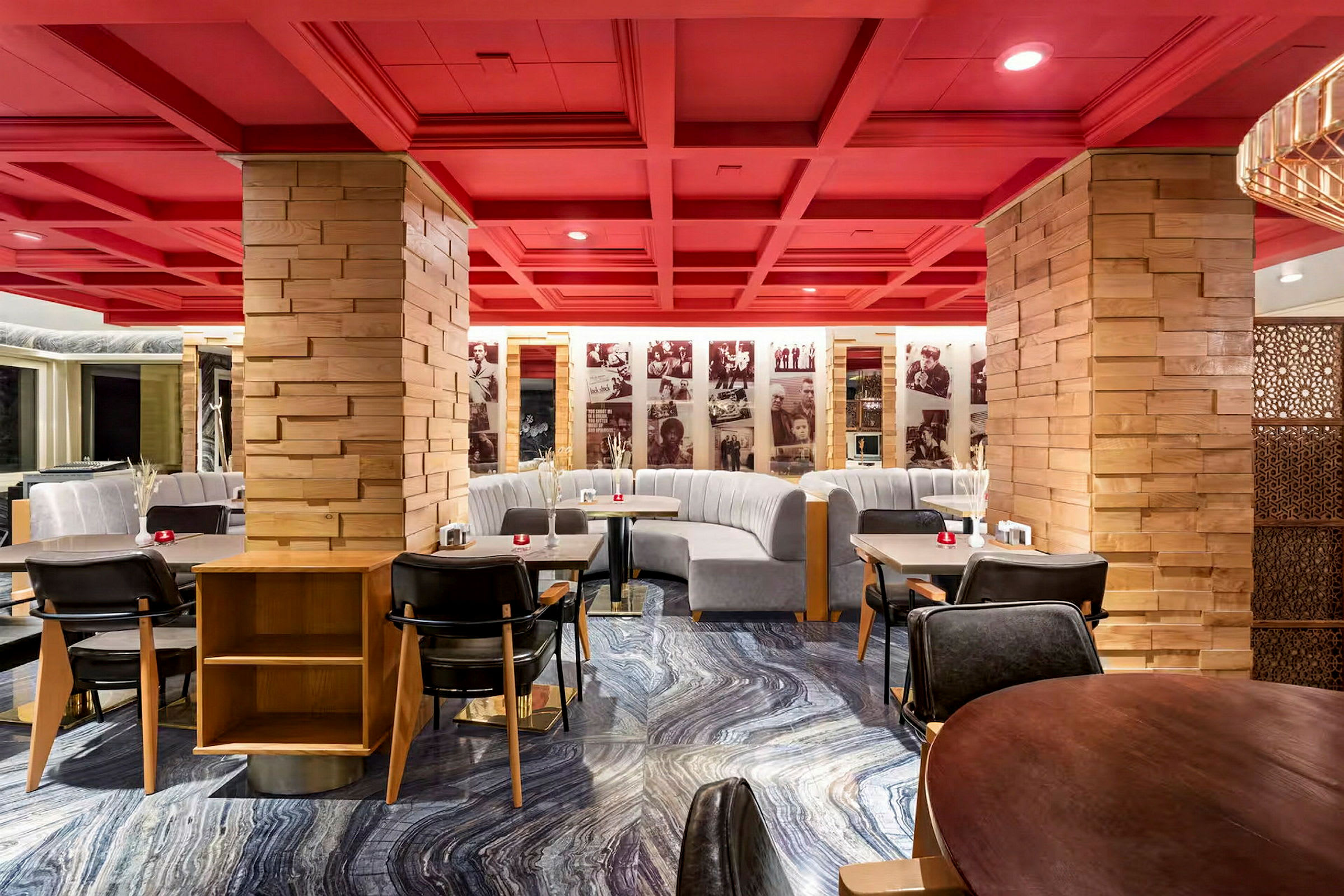 En restaurant med røde tak og trestolper samt grå sofaer og moderne spisebord. (AI-generert tekst)