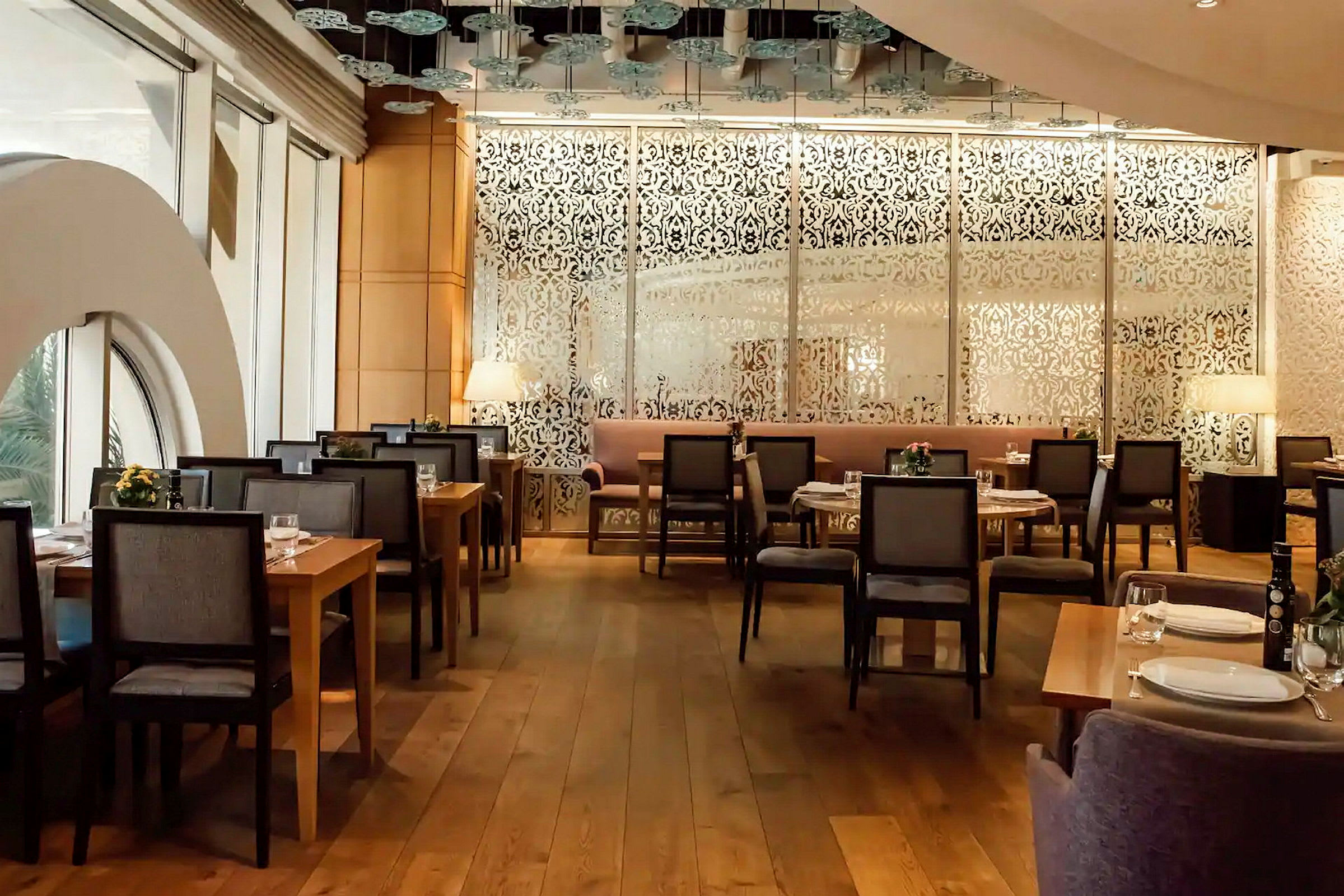En fin restaurant med dekorative mønstrede skjermer og trebord omgitt av stoler. (AI-generert tekst)
