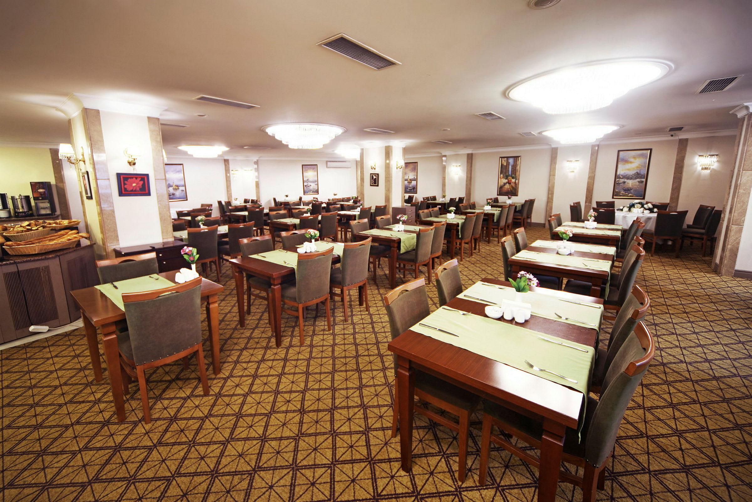 Restaurant med flere oppstilte bord og stoler, dekket med grønne underlag og blomsterdekorasjoner. (AI-generert tekst)