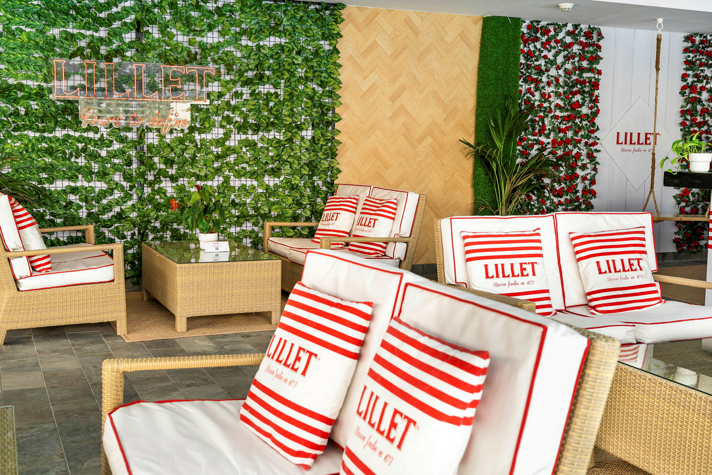 Et rom med rottingmøbler og planter, dekorert med puter med teksten 'Lillet'. (AI-generert tekst)