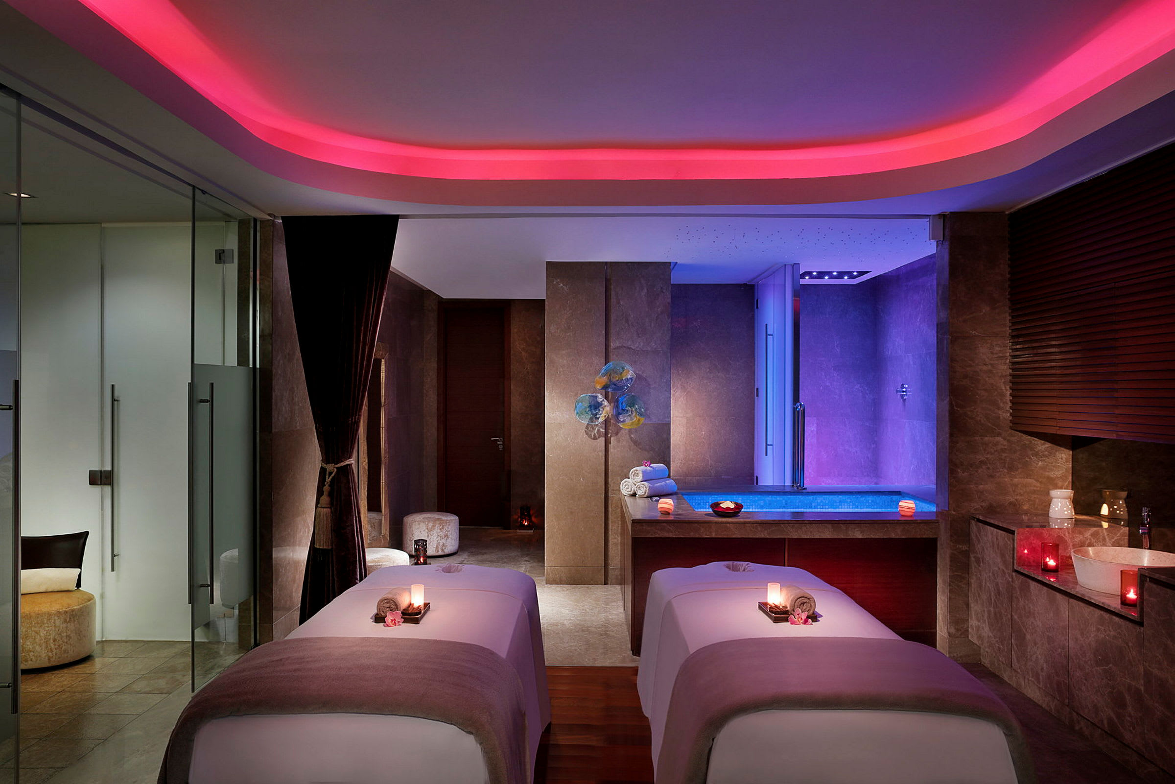 Et elegant spa-rom med to massasjebord og et opplyst bassengområde i bakgrunnen. (AI-generert tekst)