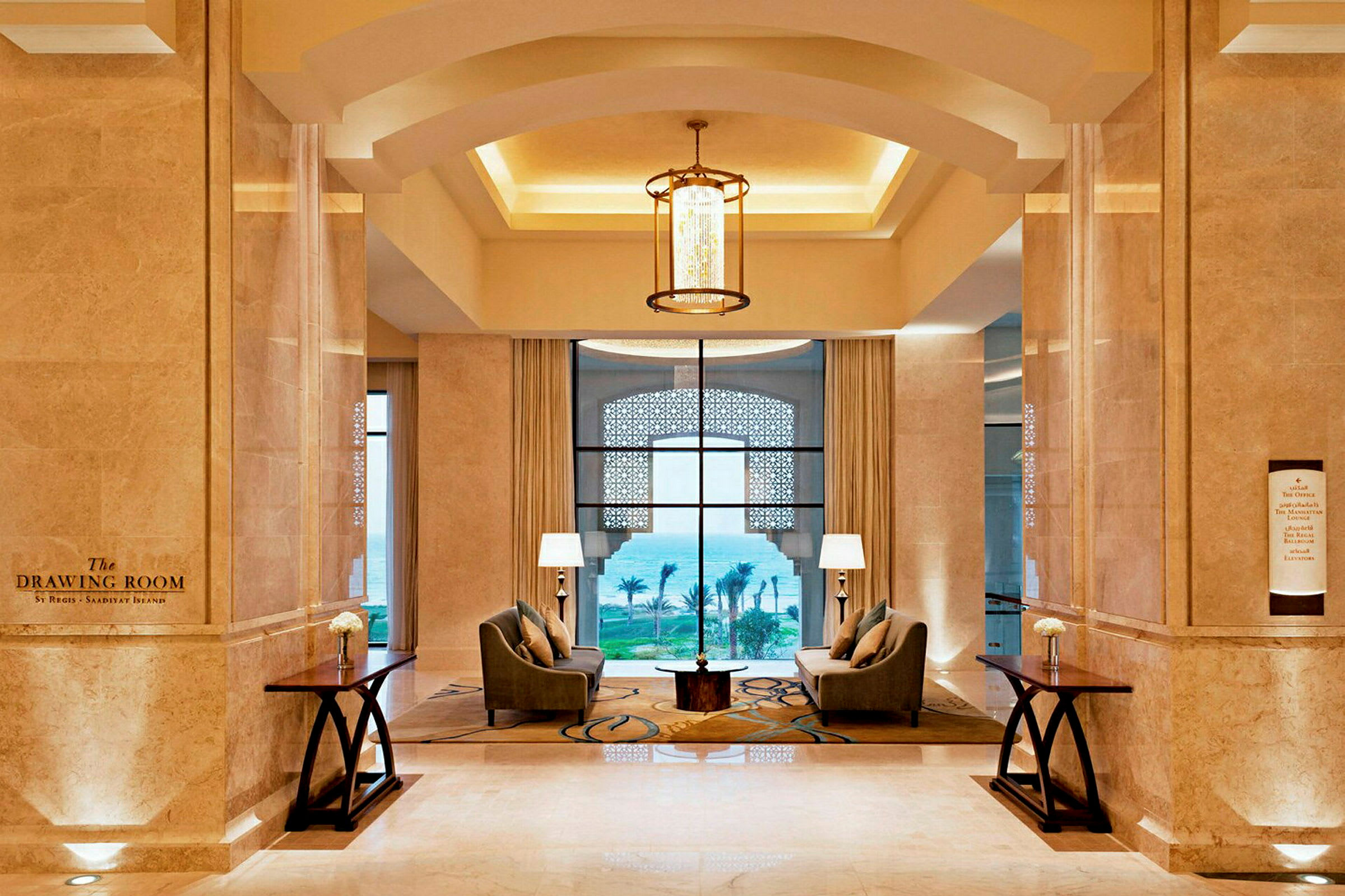 Elegant hotellobby med to lenestoler ved et bord og store vinduer med havutsikt. (AI-generert tekst)