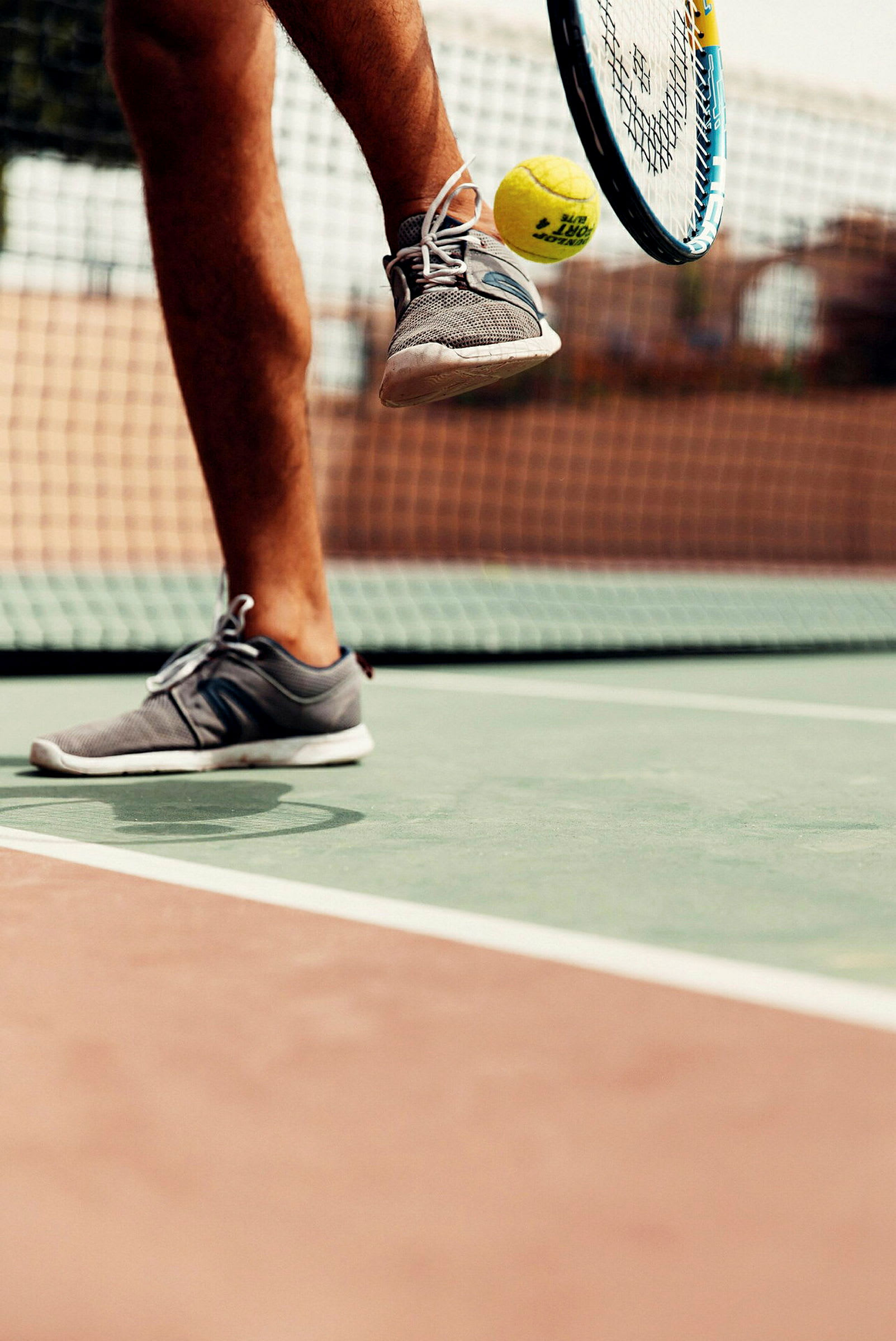 En tennisspiller på en bane slår en tennisball med racketen sin. (AI-generert tekst)