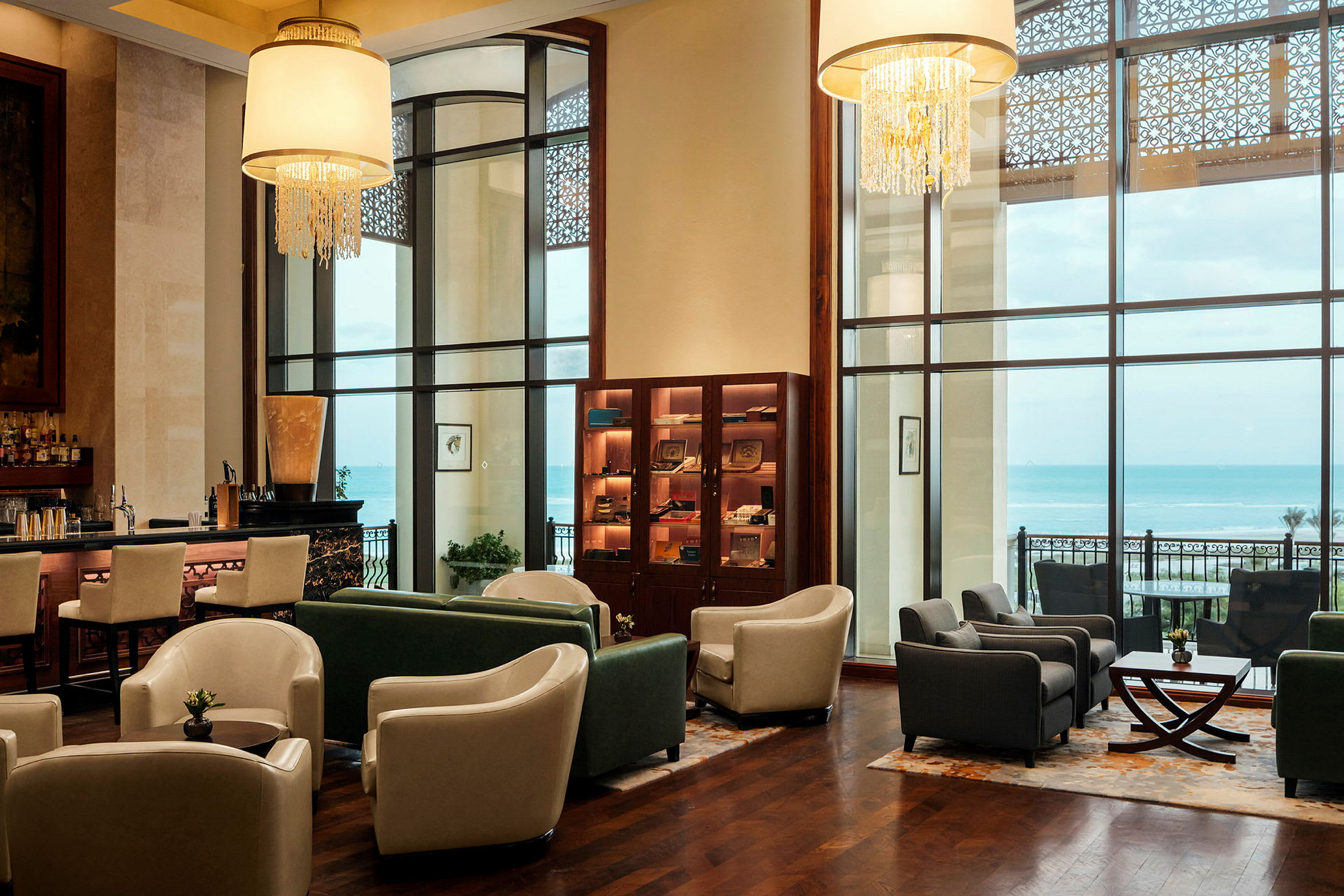 En elegant lounge med sitteplasser, bar og store vinduer som gir utsikt over havet. (AI-generert tekst)