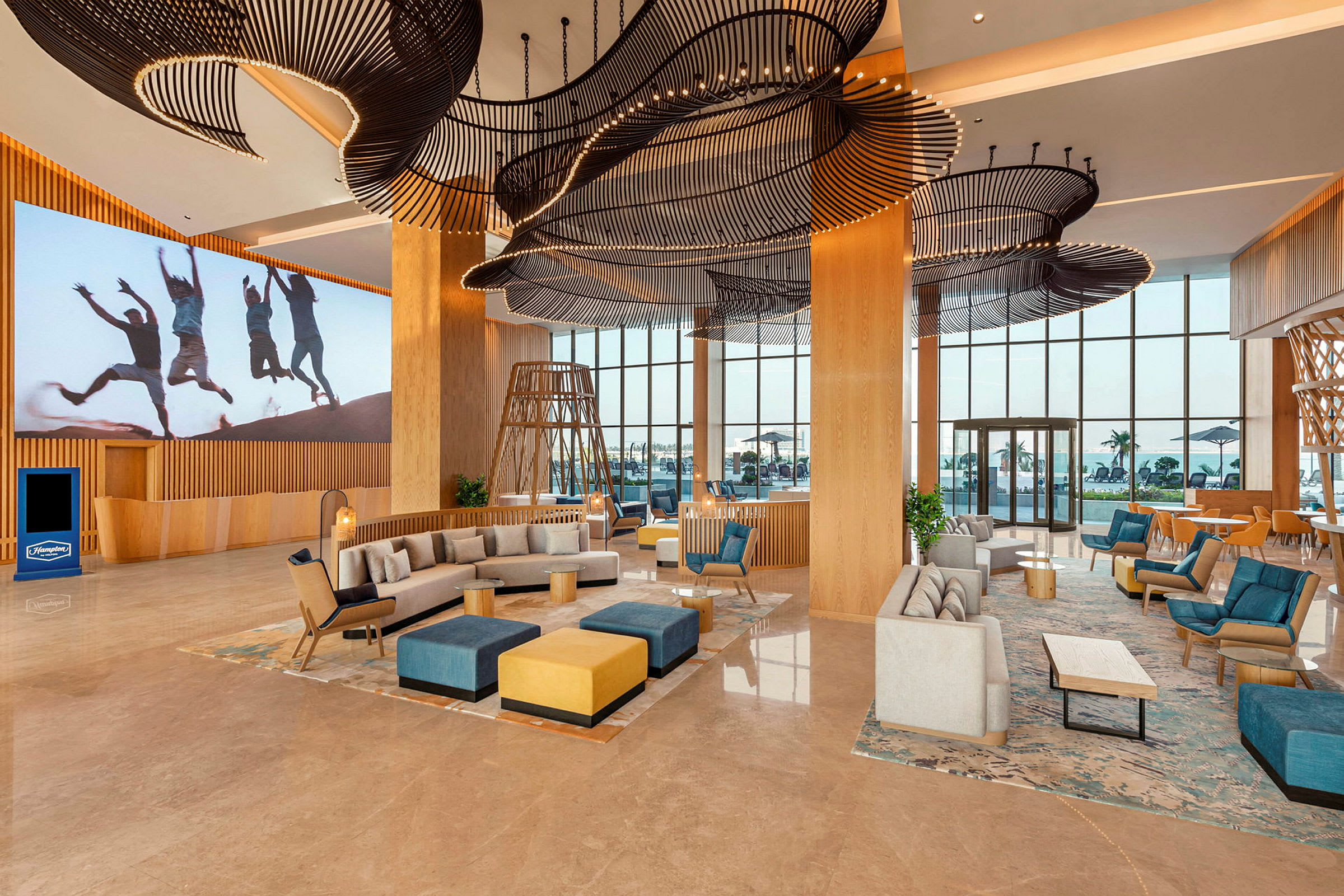 Et romslig hotellobbyområde med moderne innredning, sofaer, lenestoler og dekorative takdetaljer. (AI-generert tekst)
