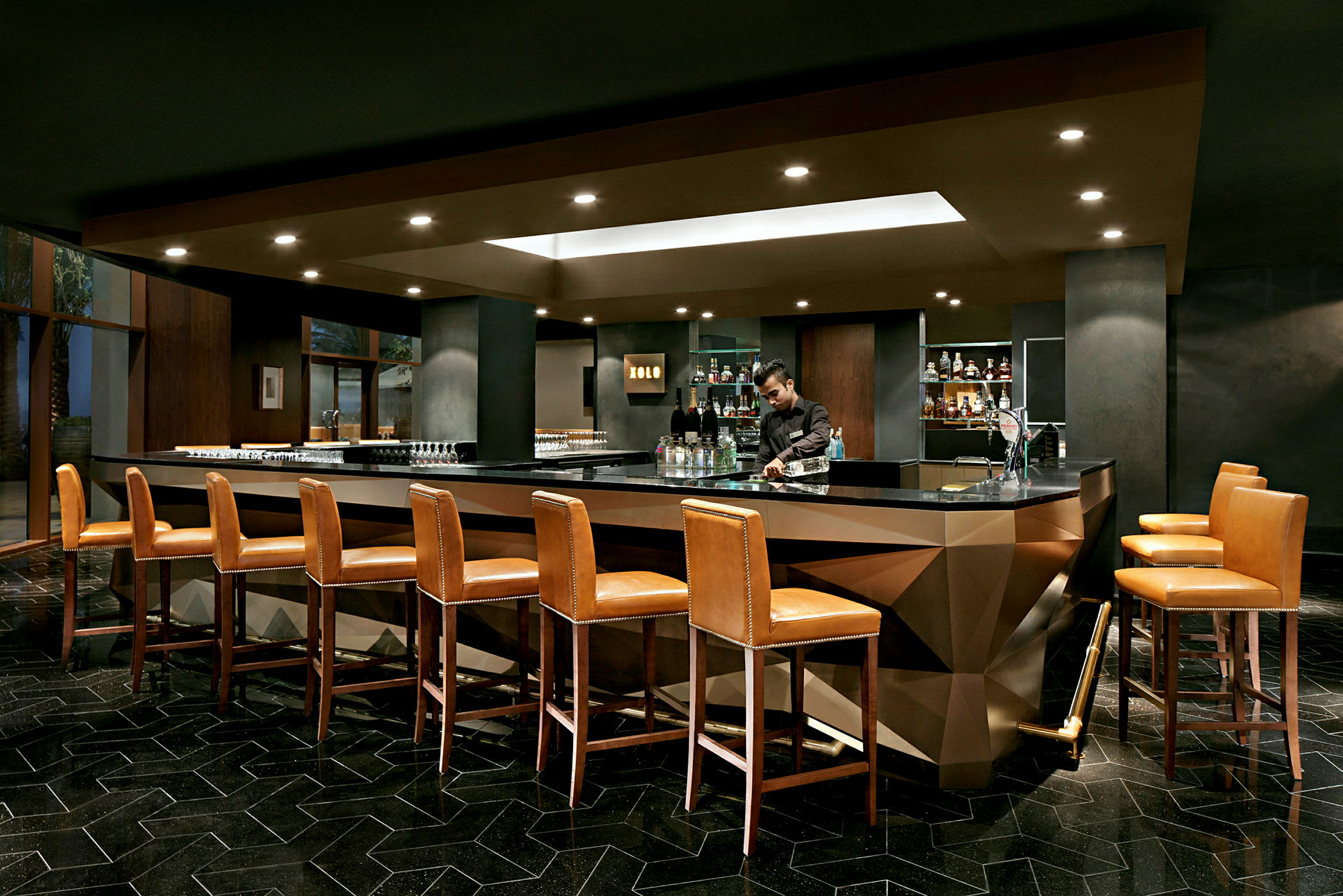 En elegant bar med høye skinnstoler plassert rundt en moderne bardisk, i et stilfullt interiør. (AI-generert tekst)