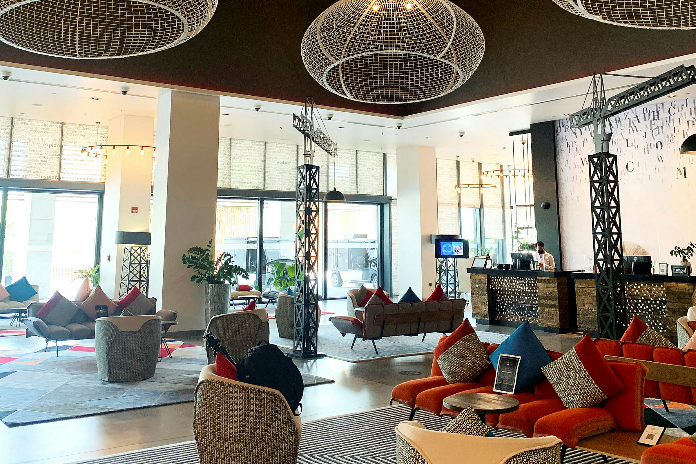 Luftig og moderne hotellobby med sittegrupper, resepsjon og dekorative elementer i taket. (AI-generert tekst)