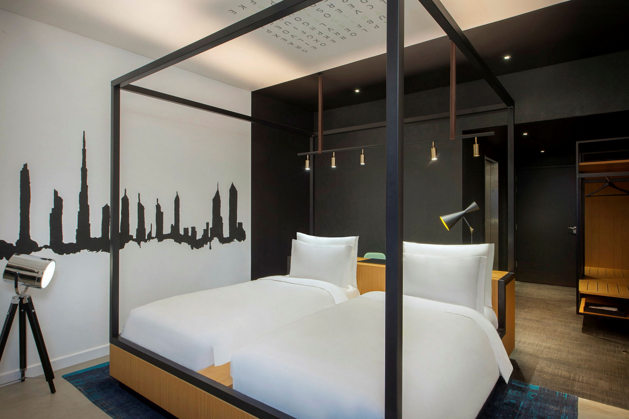 Et moderne hotellrom med to senger, svart-hvitt veggdekor og minimalistisk interiør. (AI-generert tekst)
