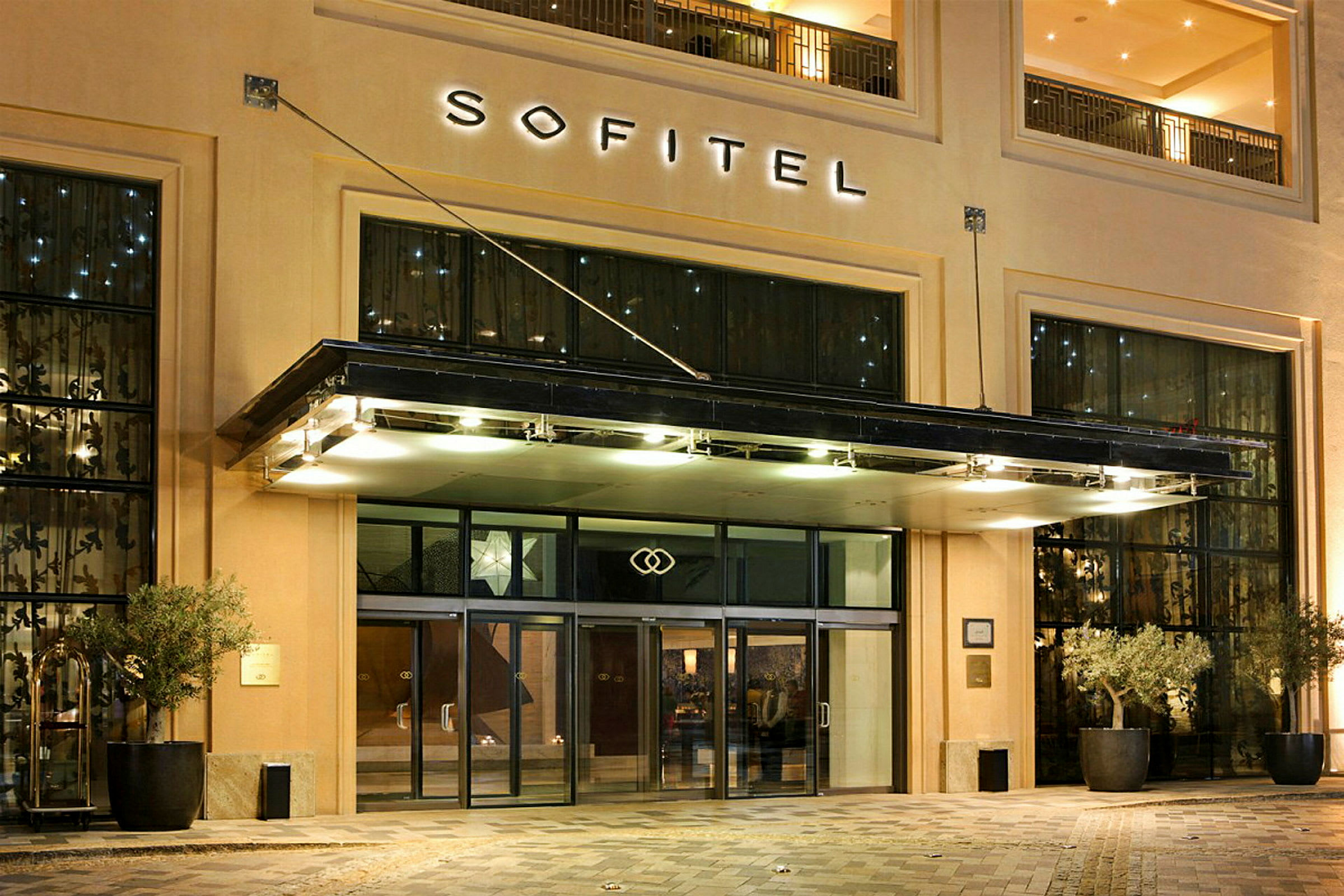 Inngangen til hotell Sofitel med glassdører og belysning. (AI-generert tekst)
