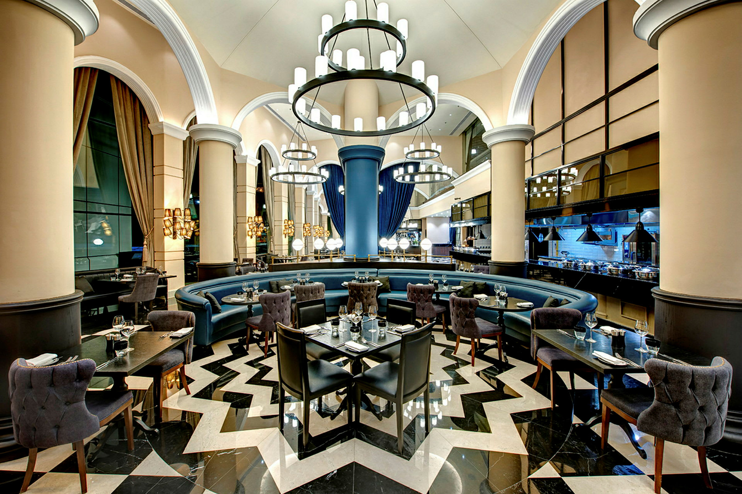 En elegant restaurant med høyt tak, lysekroner, rund sitteområde og moderne møbler. (AI-generert tekst)