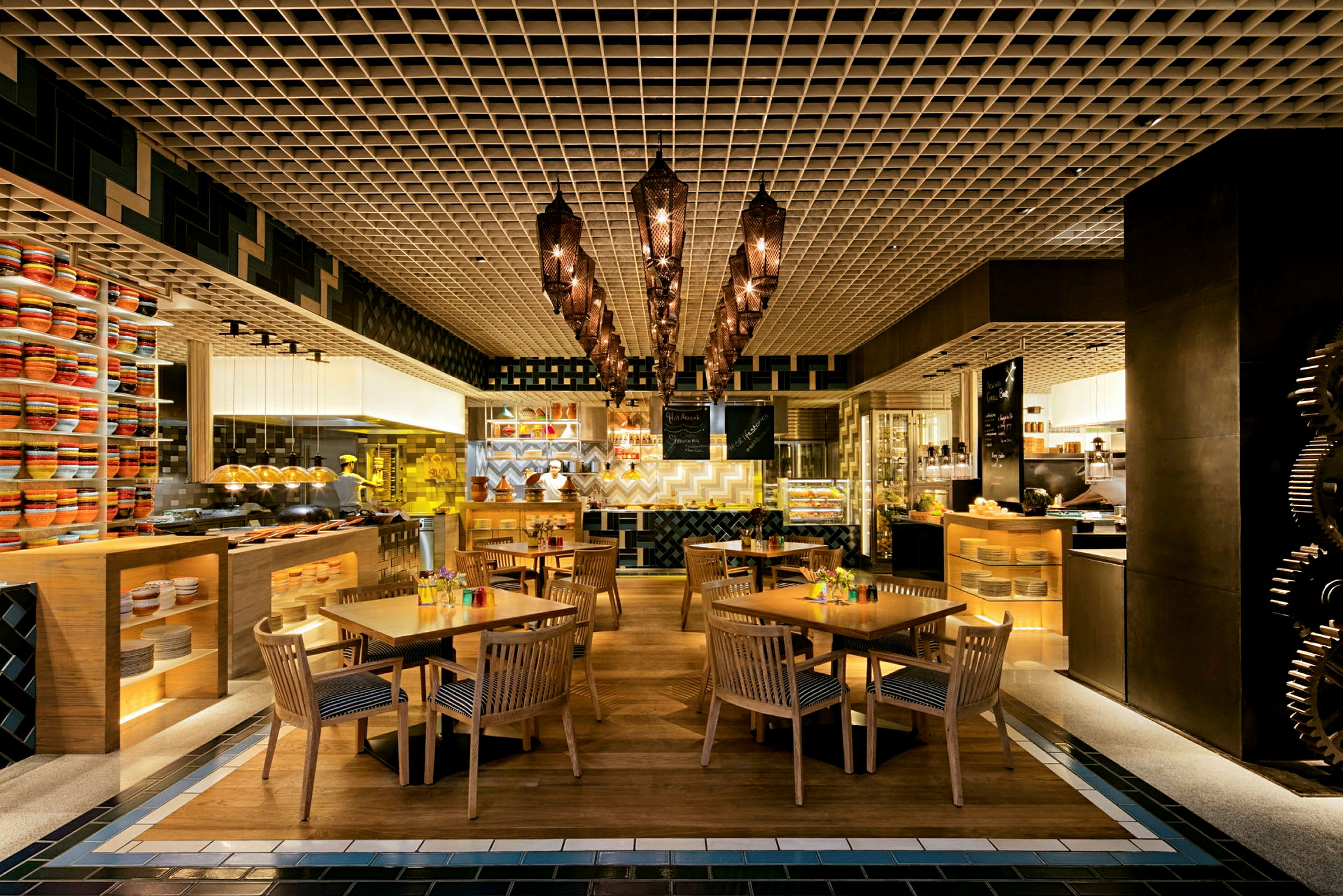 Restaurant med trebord og stoler, samt dekorative lys og hyller med fargerike gjenstander. (AI-generert tekst)