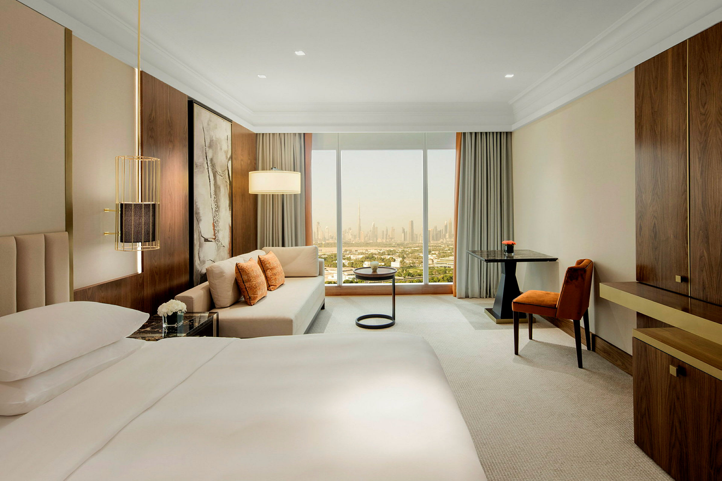 Moderne hotellrom med stor seng, sofagruppe og vindu med utsikt over byens silhuett. (AI-generert tekst)