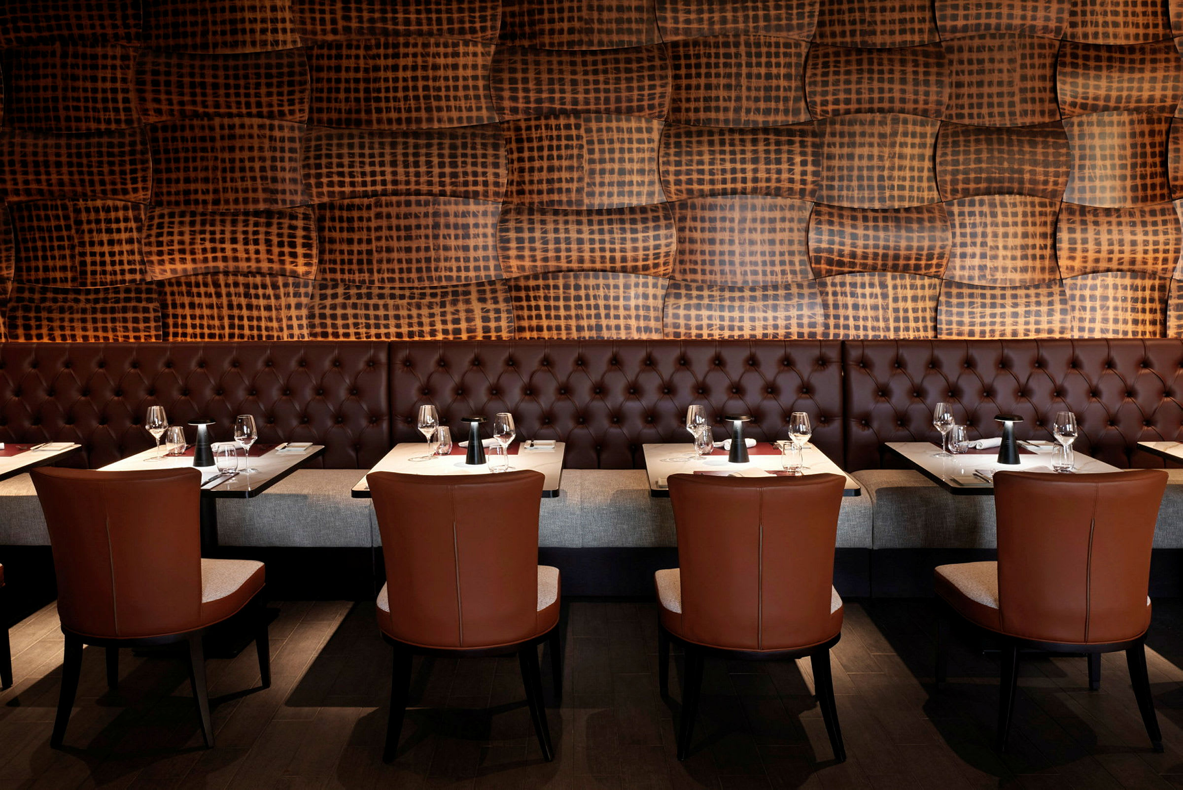 En restaurantmiljø med sofaer, bord og stoler samt en vegg med et dekorativt mønster. (AI-generert tekst)