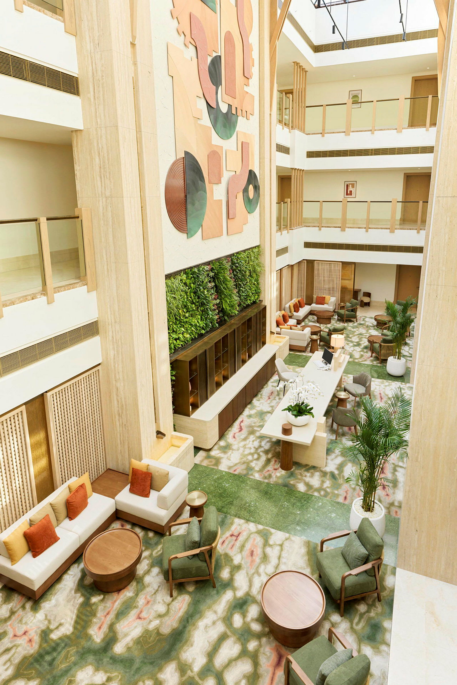 Hotellobby med sittegrupper, grønn plantevegg og moderne kunst på veggen. (AI-generert tekst)