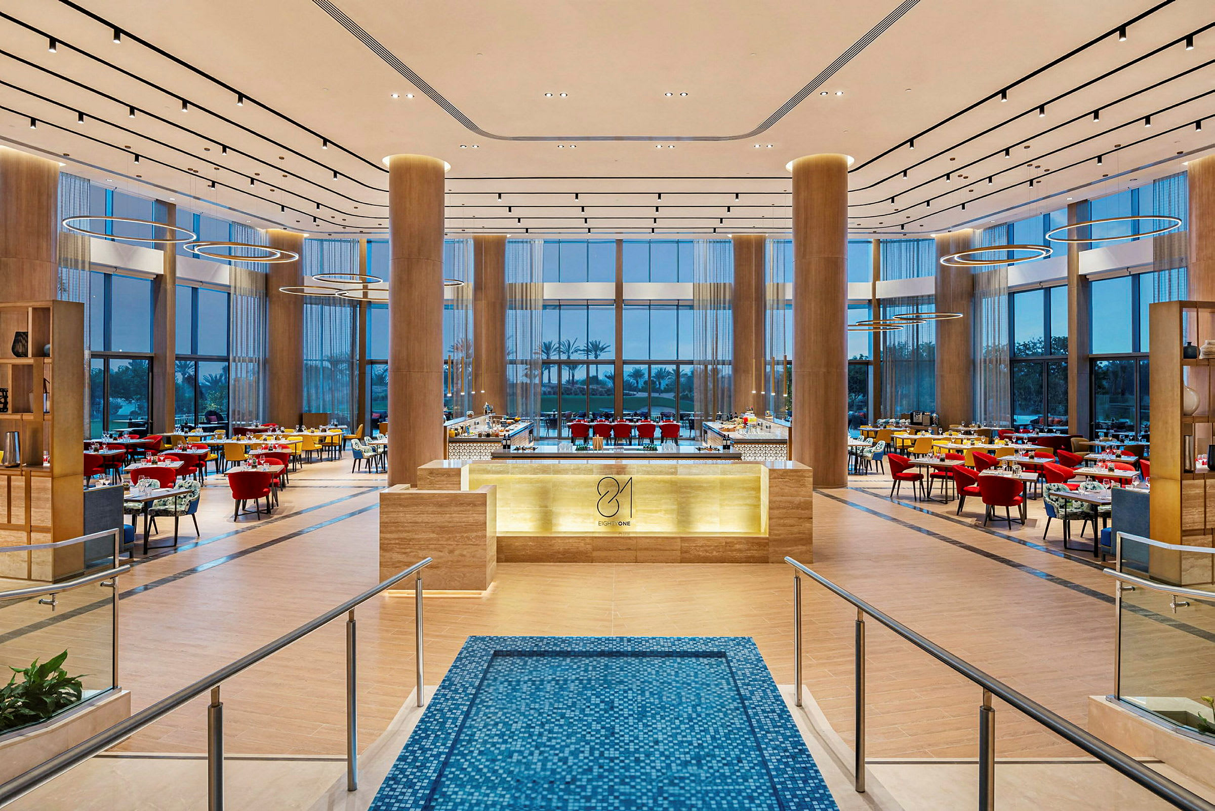 Stor og elegant restaurant med høyt tak, moderne innredning og store vinduer. (AI-generert tekst)