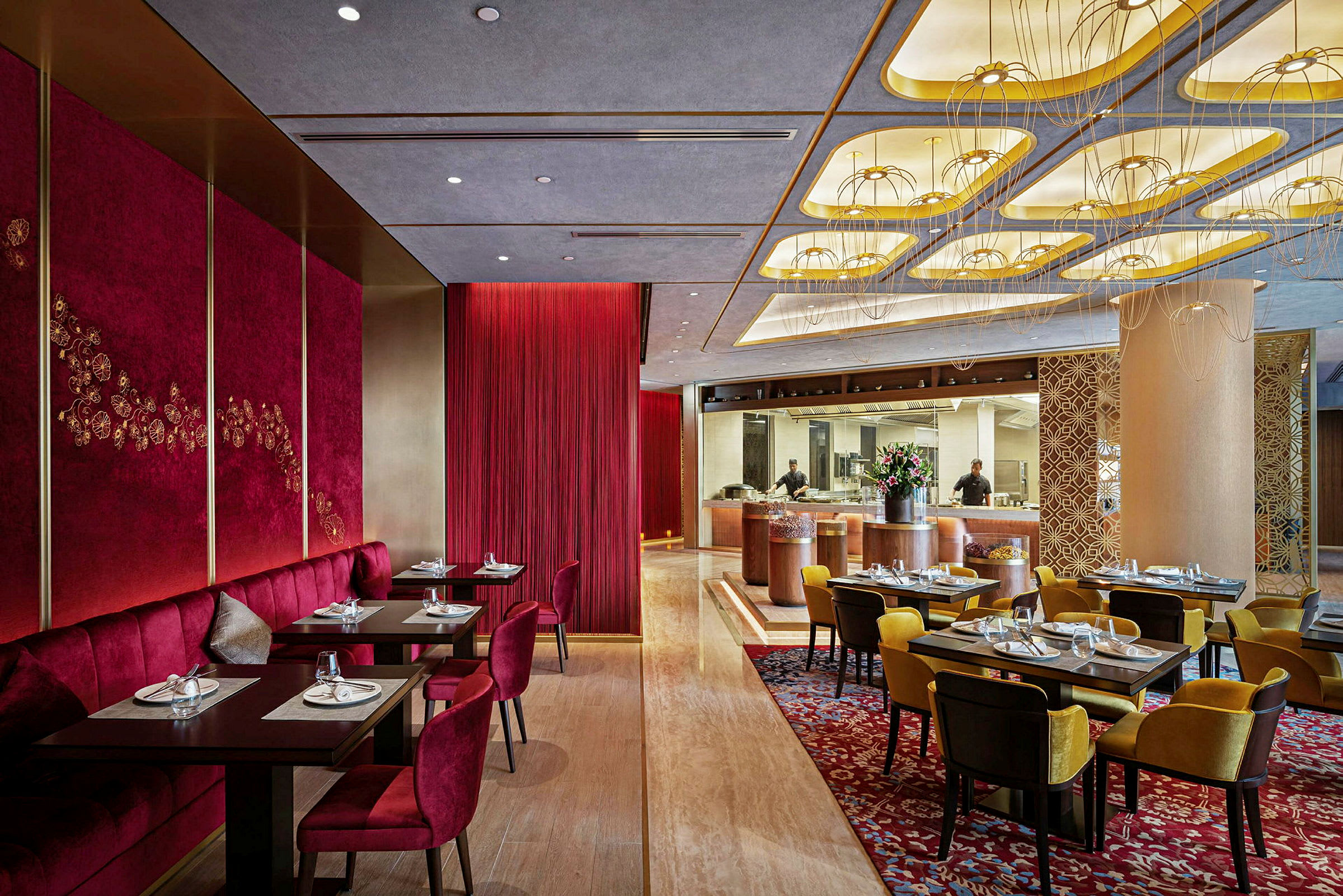 En elegant restaurant med rødt og gull på veggene samt dekorerte bord og stoler. (AI-generert tekst)