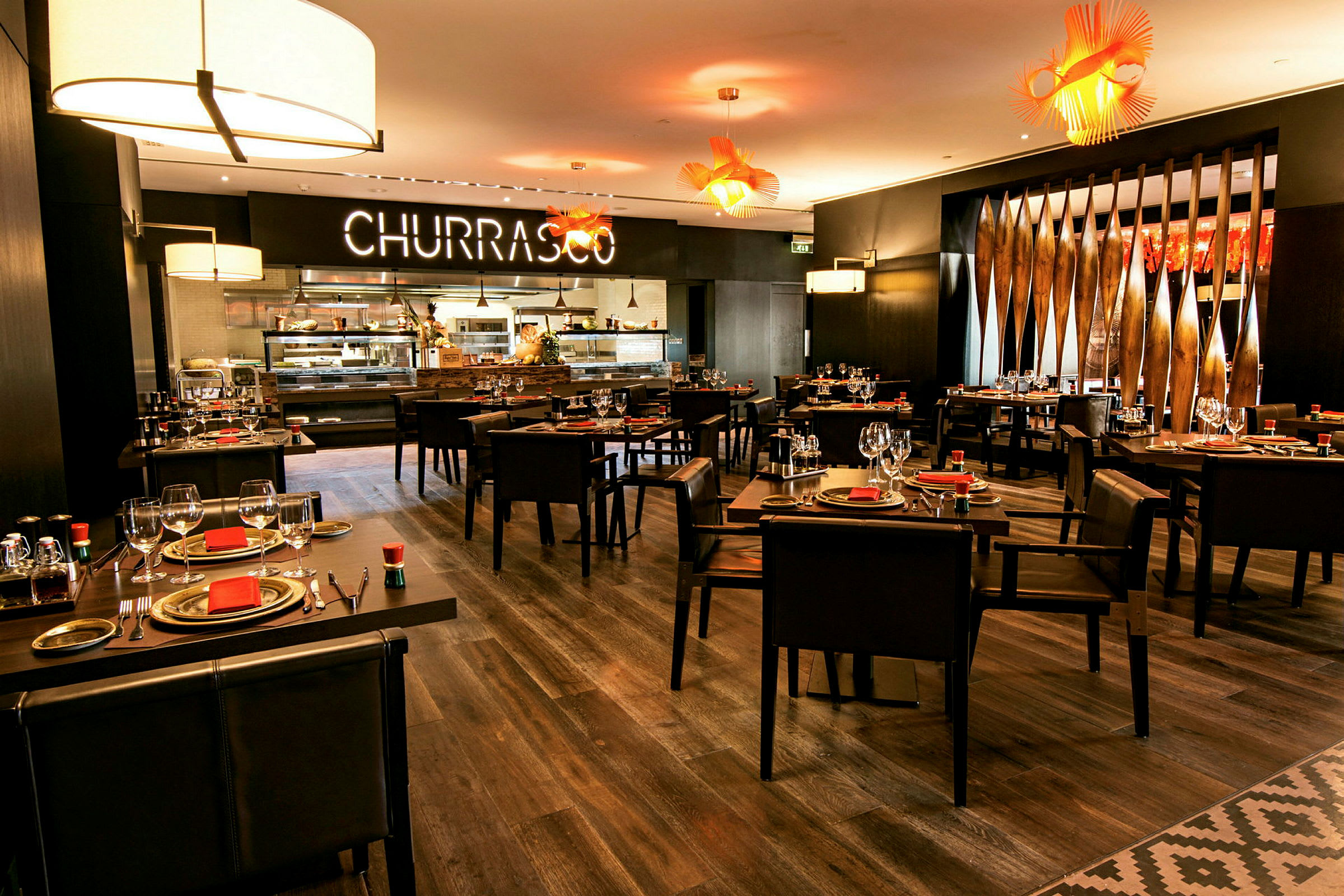 Restaurant med bord dekket med tallerkener og glass under moderne belysning. (AI-generert tekst)