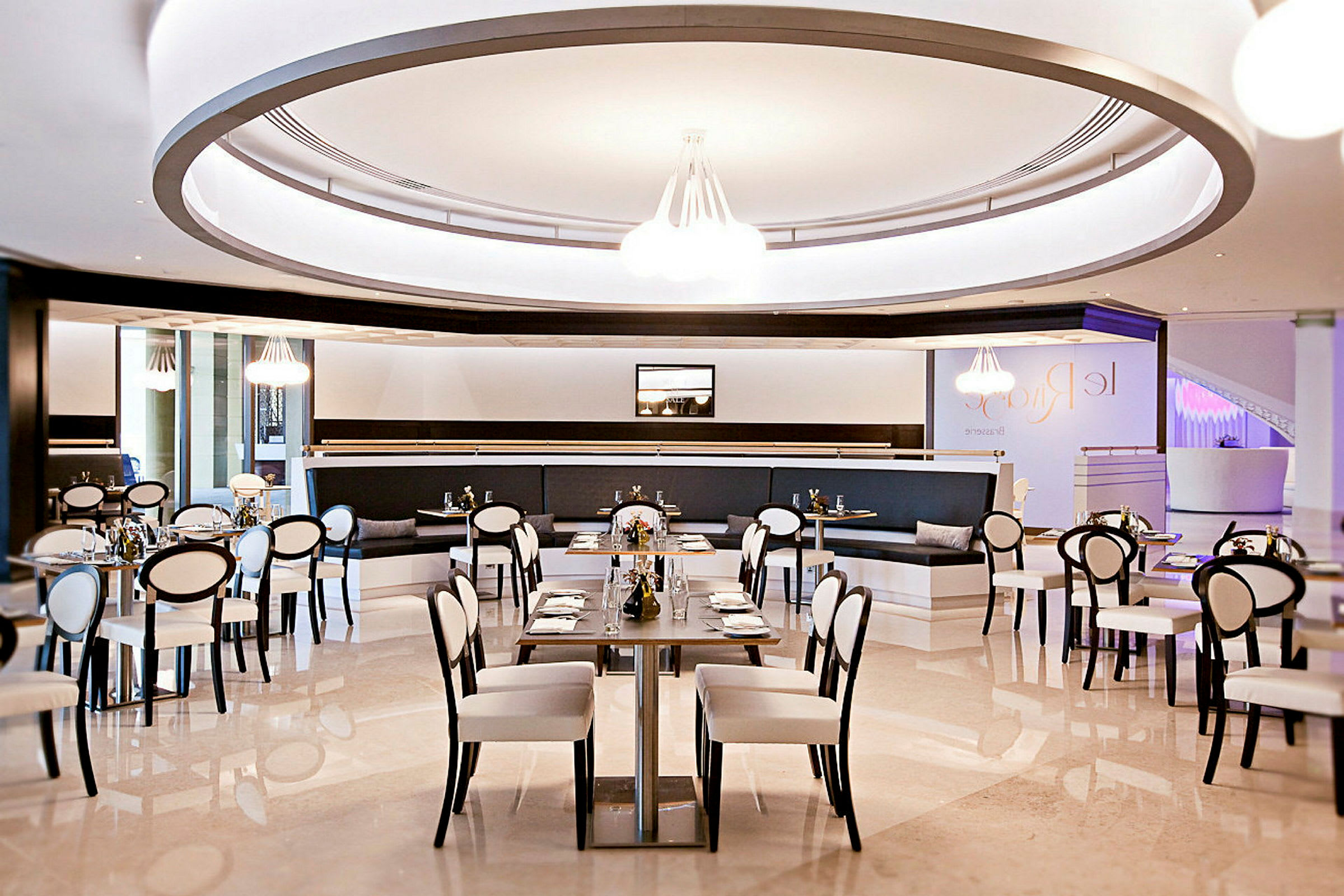 Bilde av en moderne restaurant med elegant interiør, hvite stoler med svarte rammer og dekket bord. (AI-generert tekst)