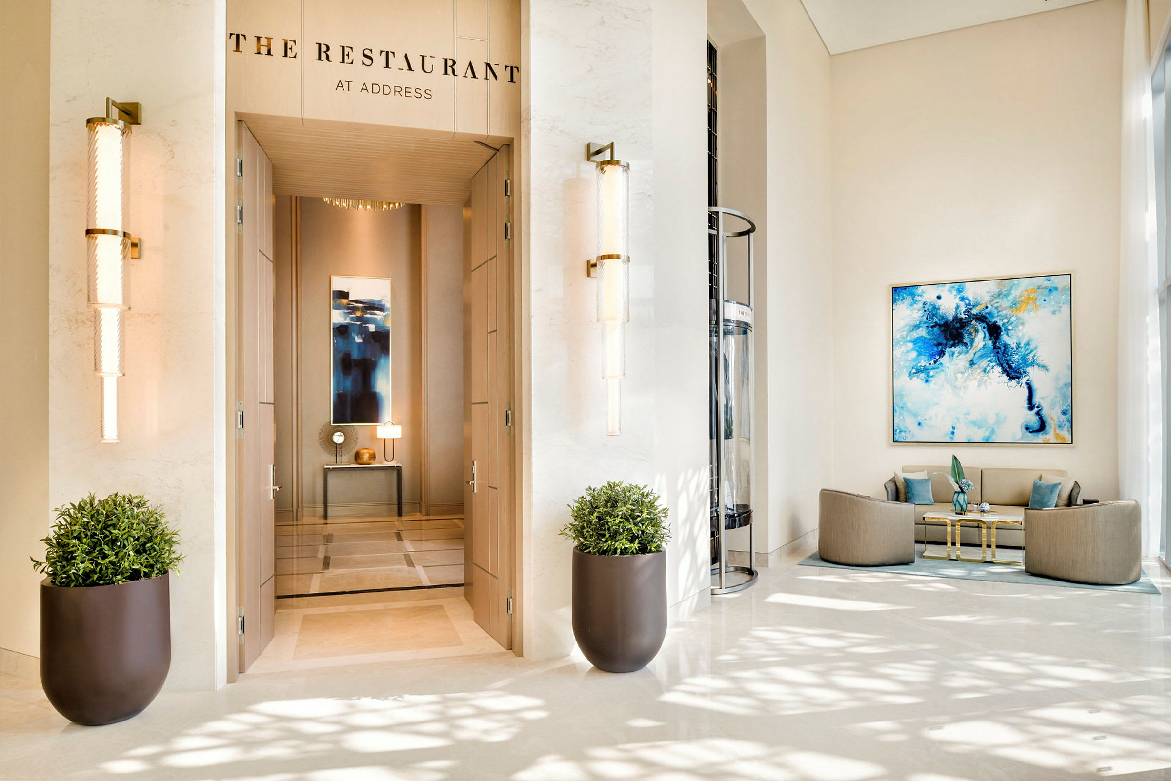 En elegant hotellobby med inngangen til "The Restaurant" synlig, to store blomsterpotter og en sittegruppe til høyre. (AI-generert tekst)
