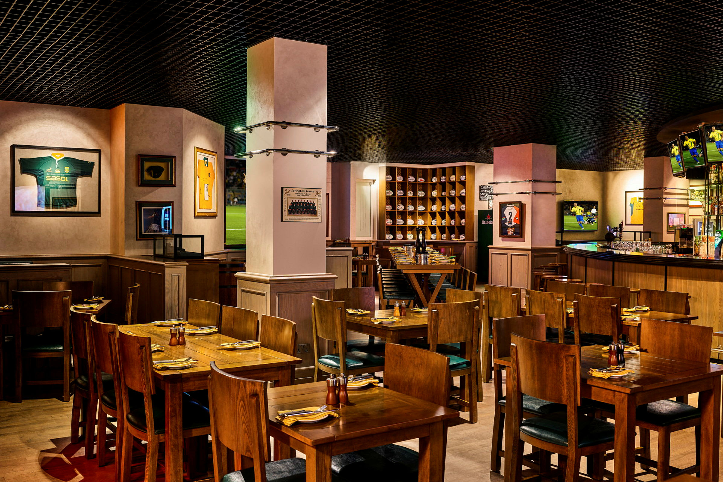 En interiør av en restaurant med trebord og stoler, dekorert med sportsminner på veggene. (AI-generert tekst)