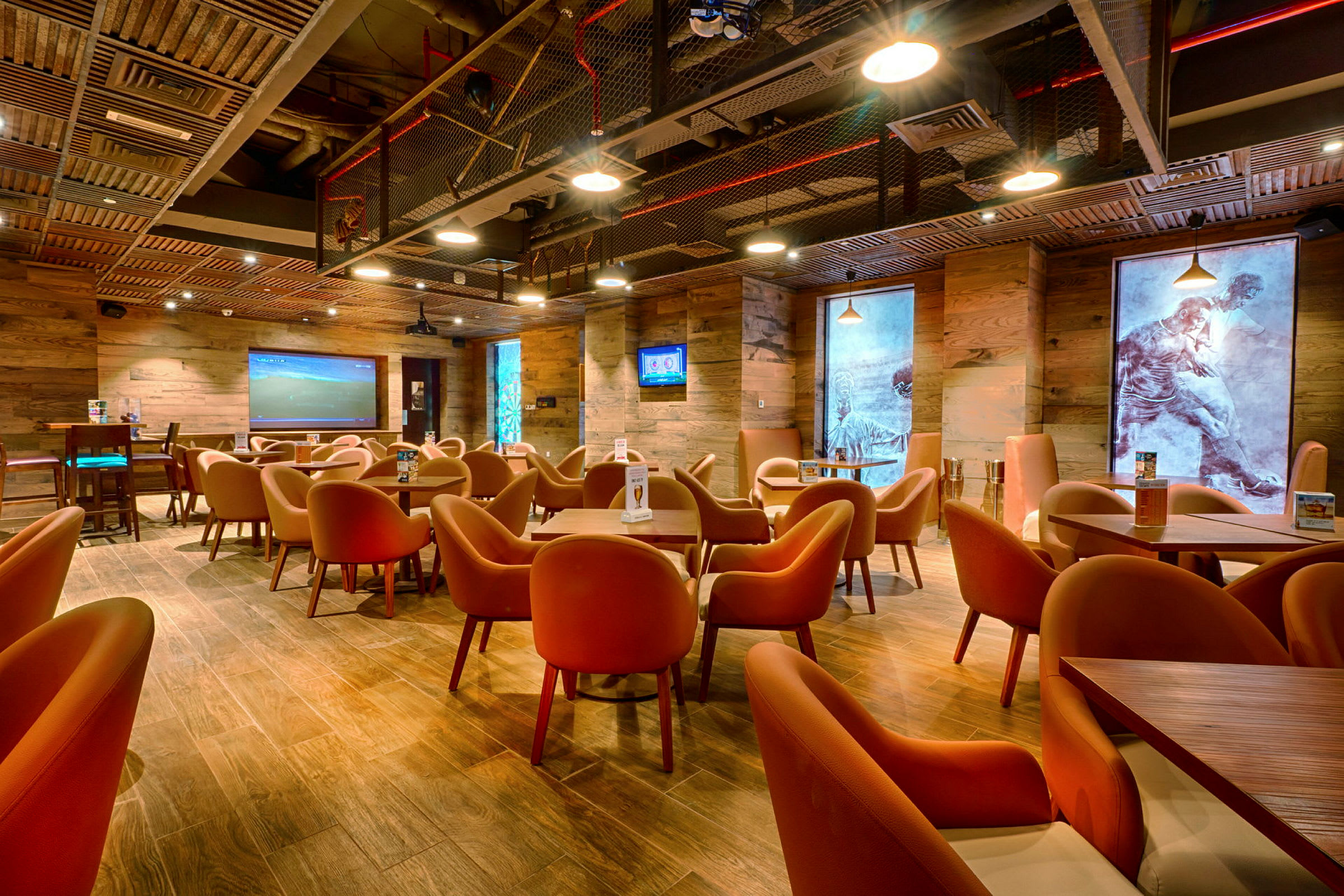 En moderne kafé eller restaurant med trevegger og oransje stoler, hvor kunstverk dekorerer veggene. (AI-generert tekst)