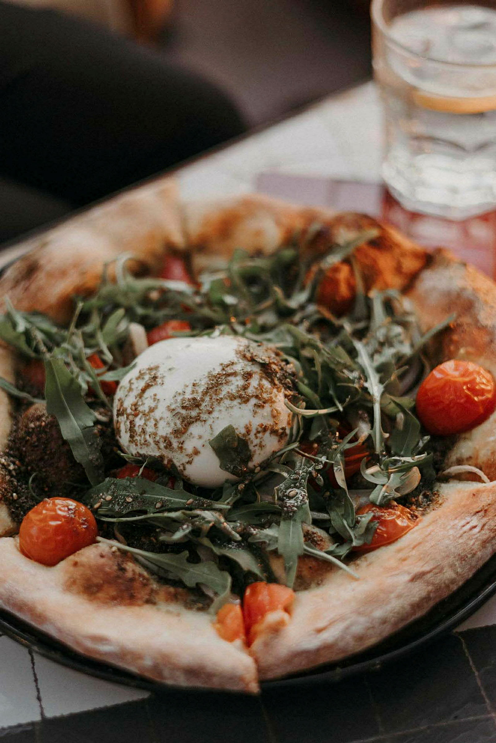 Pizza med burrataost, ruccola og cherrytomater. (AI-generert tekst)