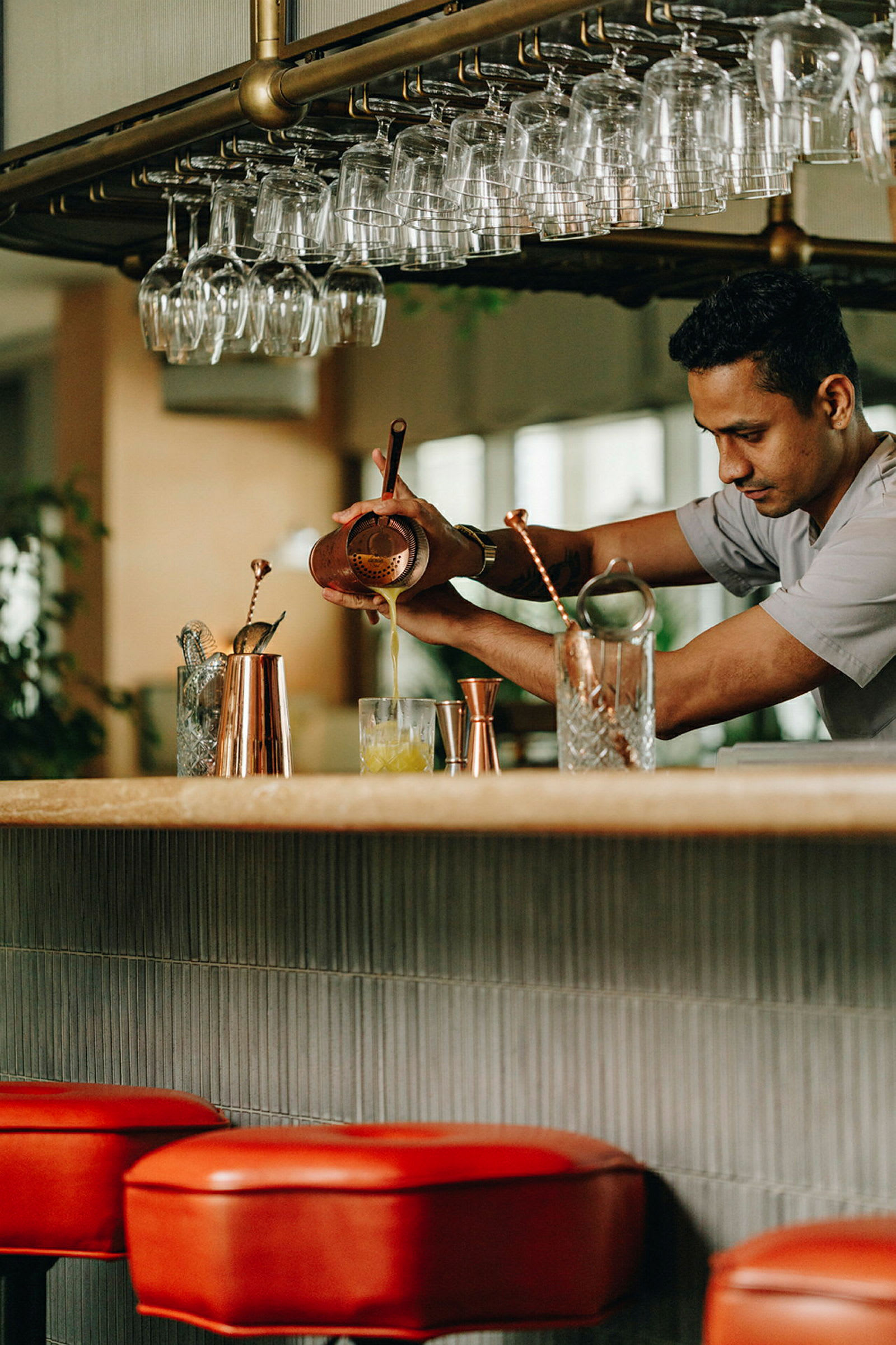 En bartender tilbereder en drink i en bar. (AI-generert tekst)
