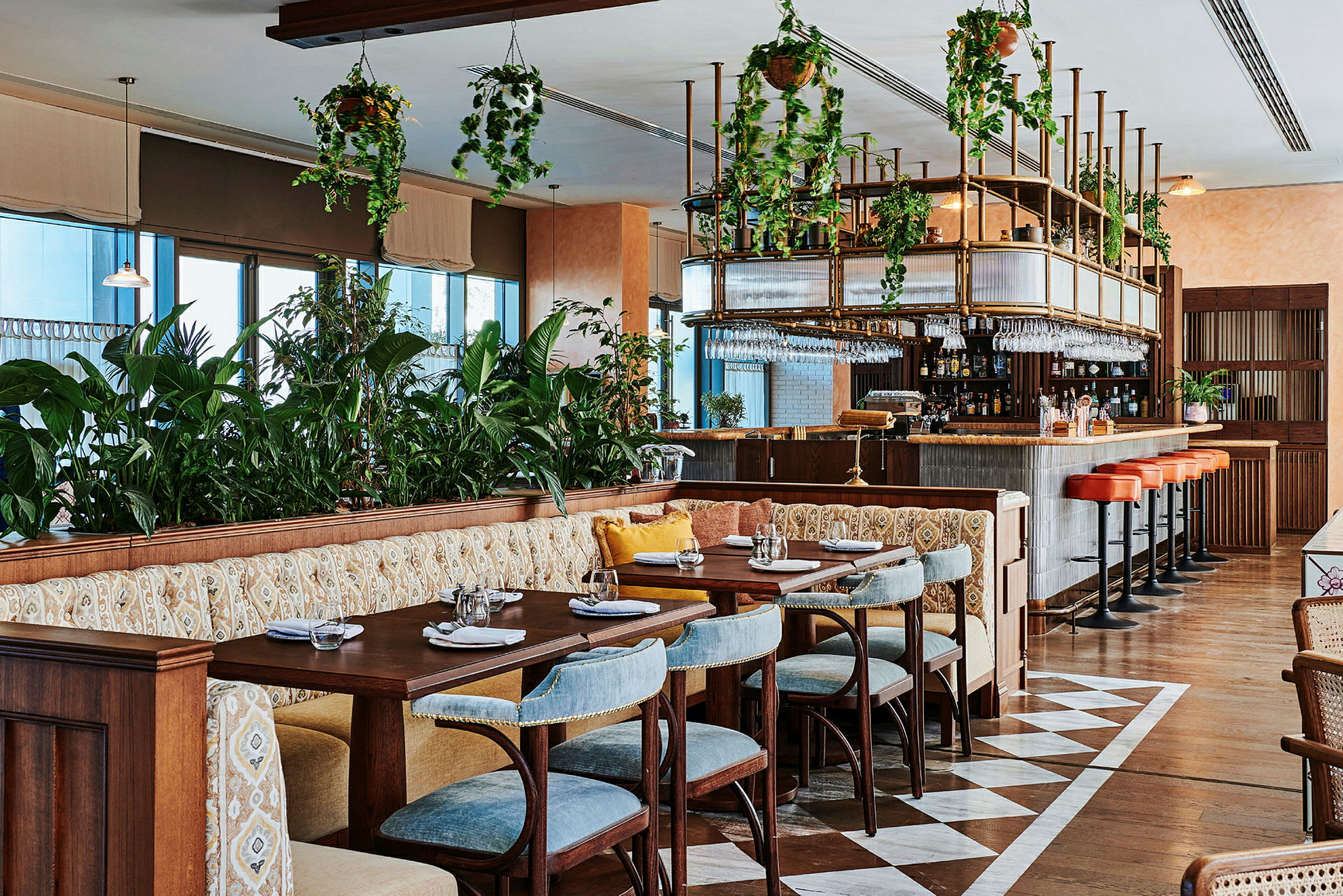 Restaurant med bord og stoler, sitteplasser og bar med hengende plantepynt. (AI-generert tekst)