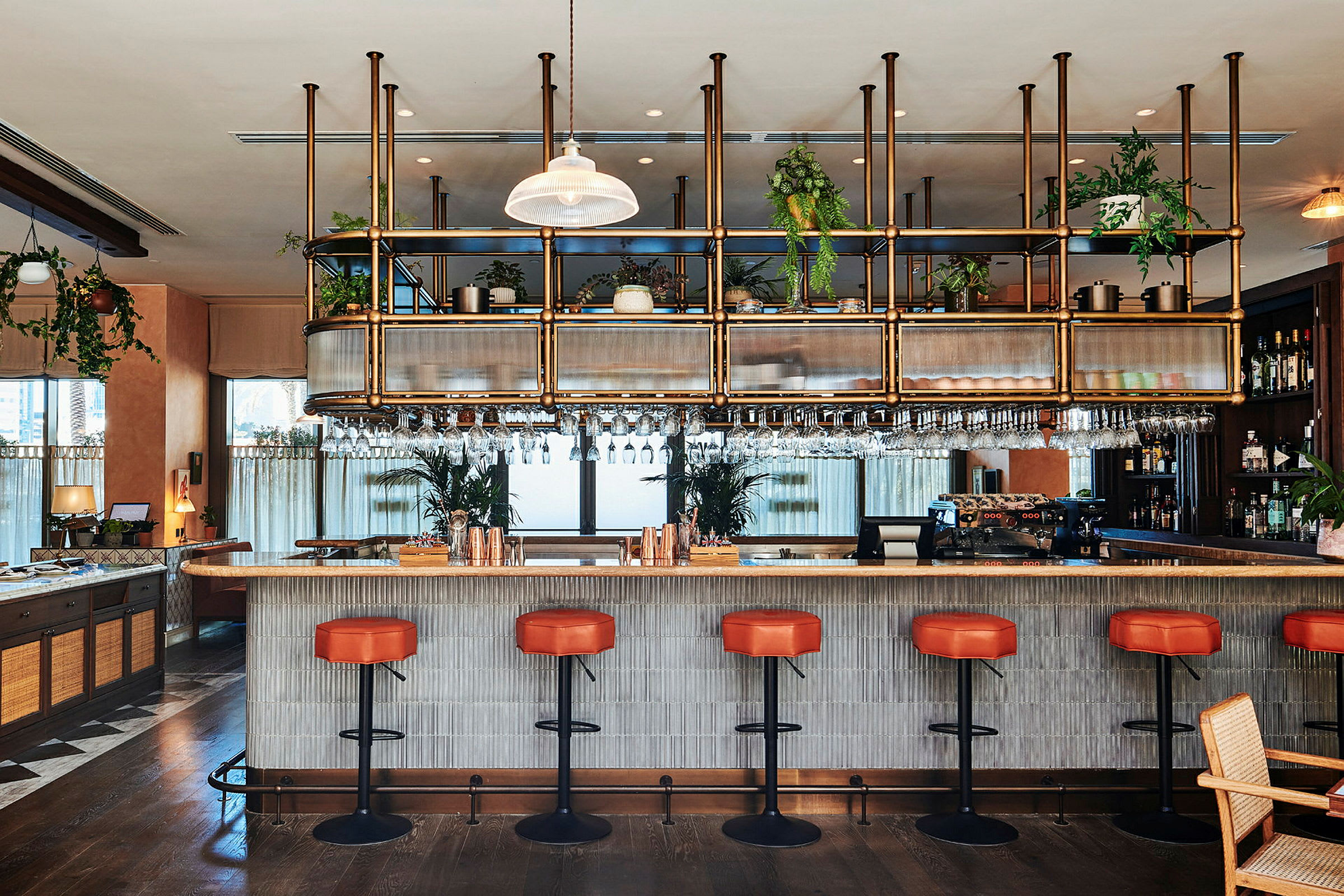 En moderne bar med røde stoler og en benkeplate med hengende glass. (AI-generert tekst)