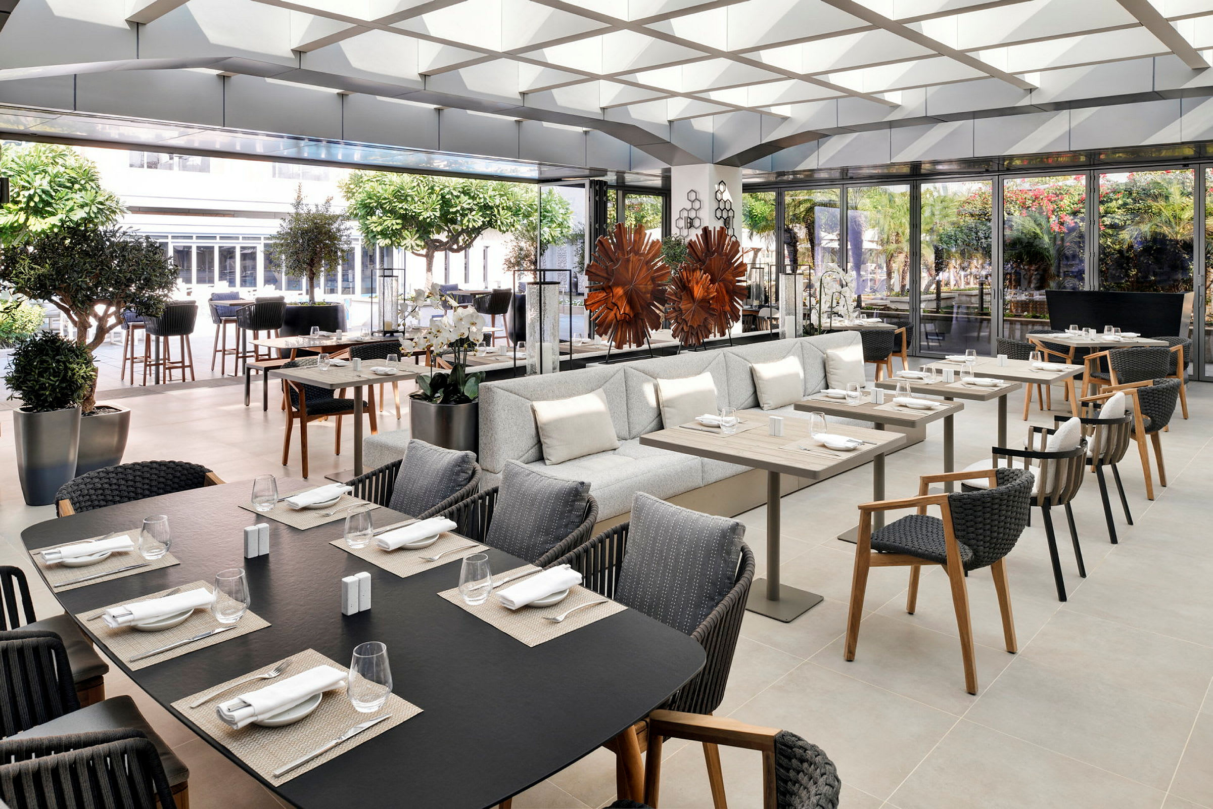 En elegant restaurant med bord og sitteplasser, dekorert med planter og moderne innredning. (AI-generert tekst)