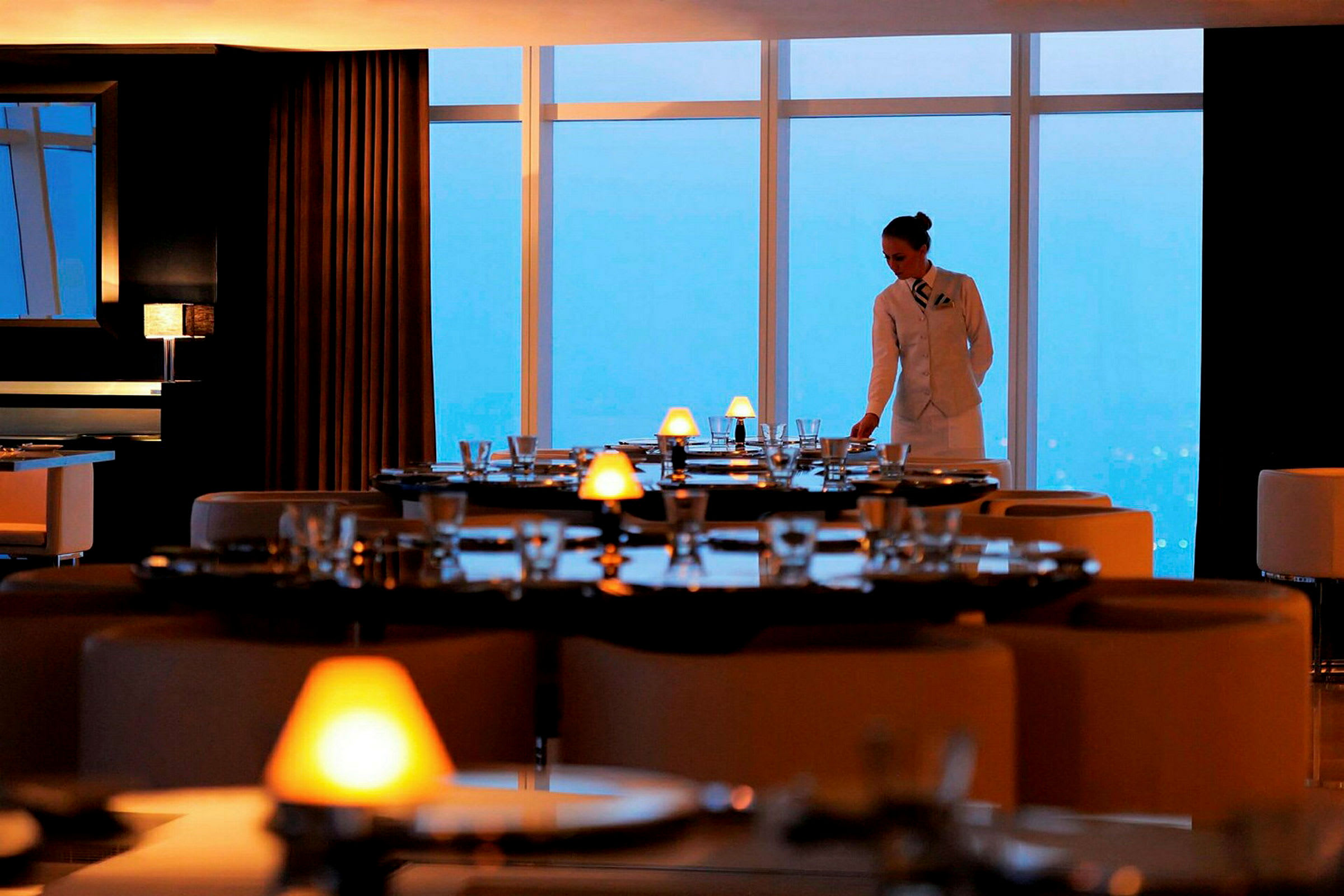 En restaurant med elegant dekke bord og store vinduer med utsikt. (AI-generert tekst)