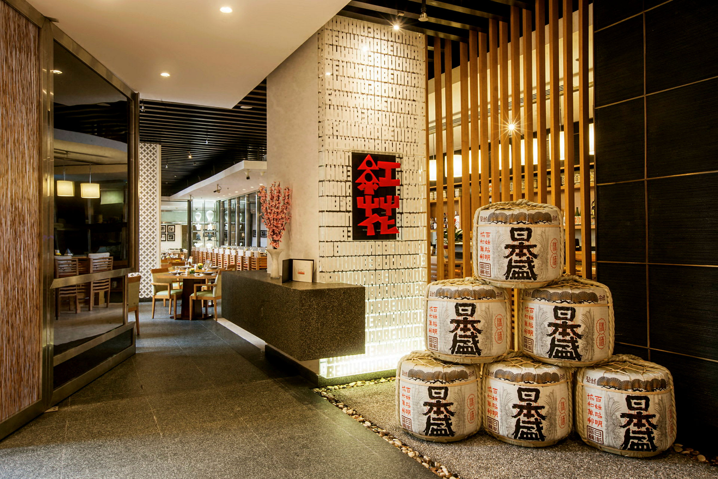 Inngangen til en elegant restaurant med japansk dekor og risfat-liknende ornamenter stablet i hjørnet. (AI-generert tekst)