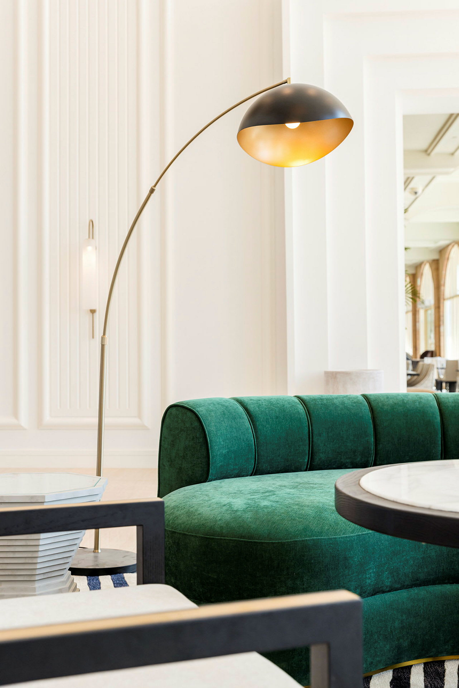En grønn sofa, en gulvlampe og et rundt bord i et lyst rom. (AI-generert tekst)