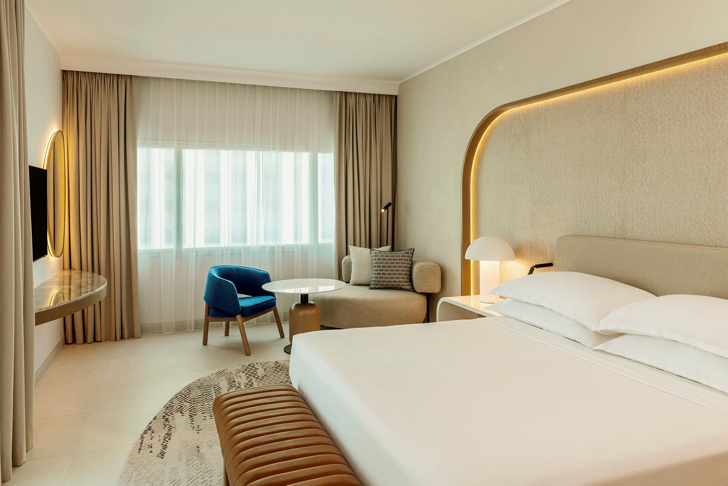 Et moderne hotellrom med en stor seng, sittegruppe og skrivebord. (AI-generert tekst)