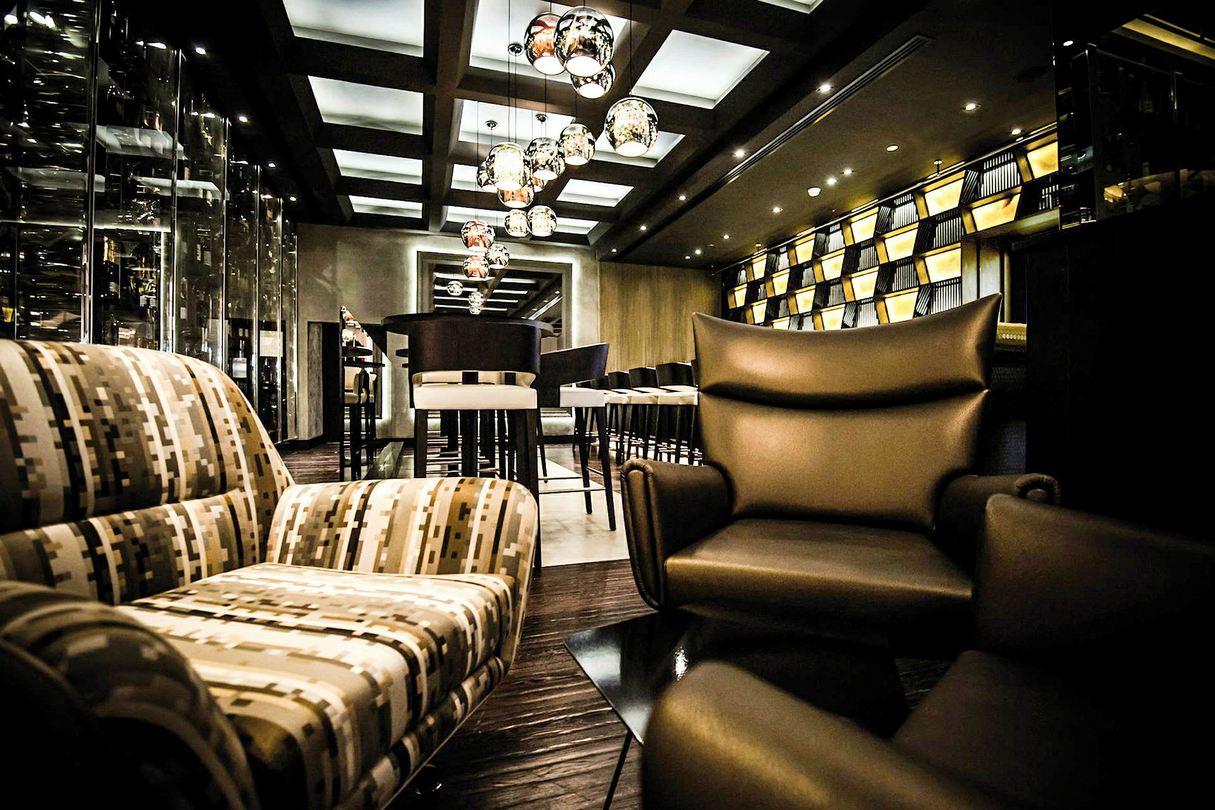 Bilde av en elegant innredet lounge med moderne sittemøbler, hengende lamper og en velstelt atmosfære. (AI-generert tekst)