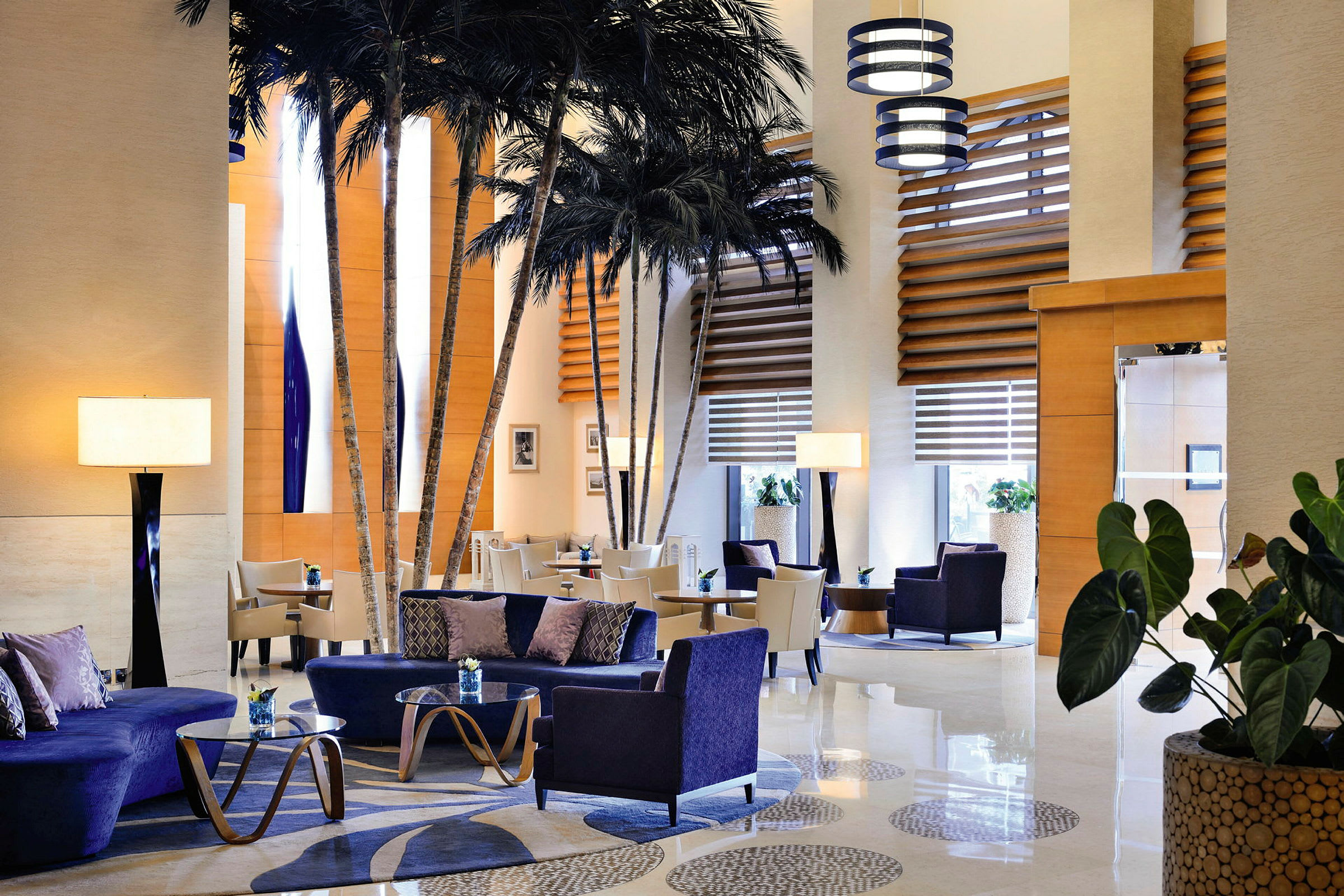 Luksuriøst innredet hotellobby med komfortable sittemøbler og dekorative palmer. (AI-generert tekst)