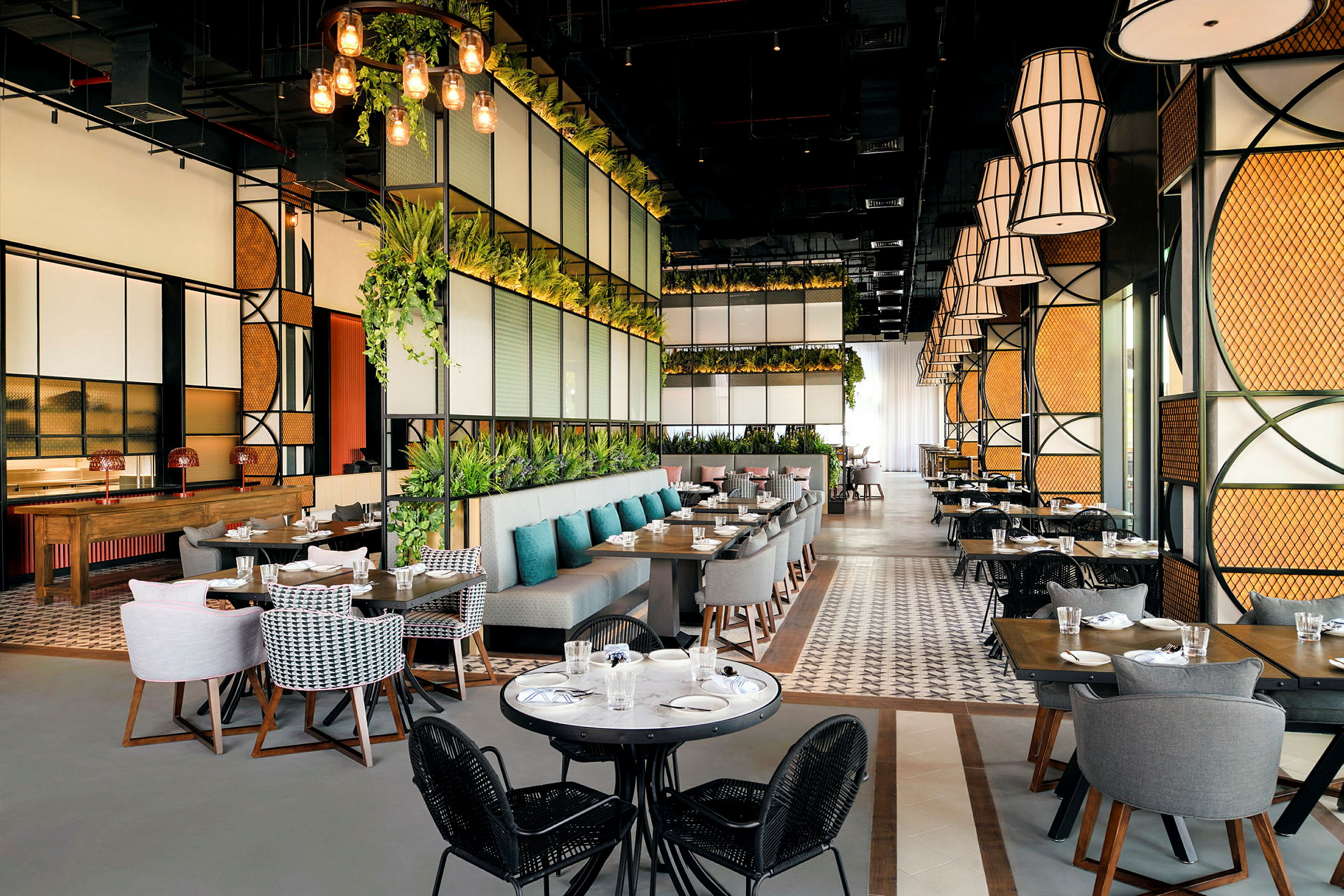En moderne restaurant med store vinduer, grønne planter og elegante sittegrupper. (AI-generert tekst)