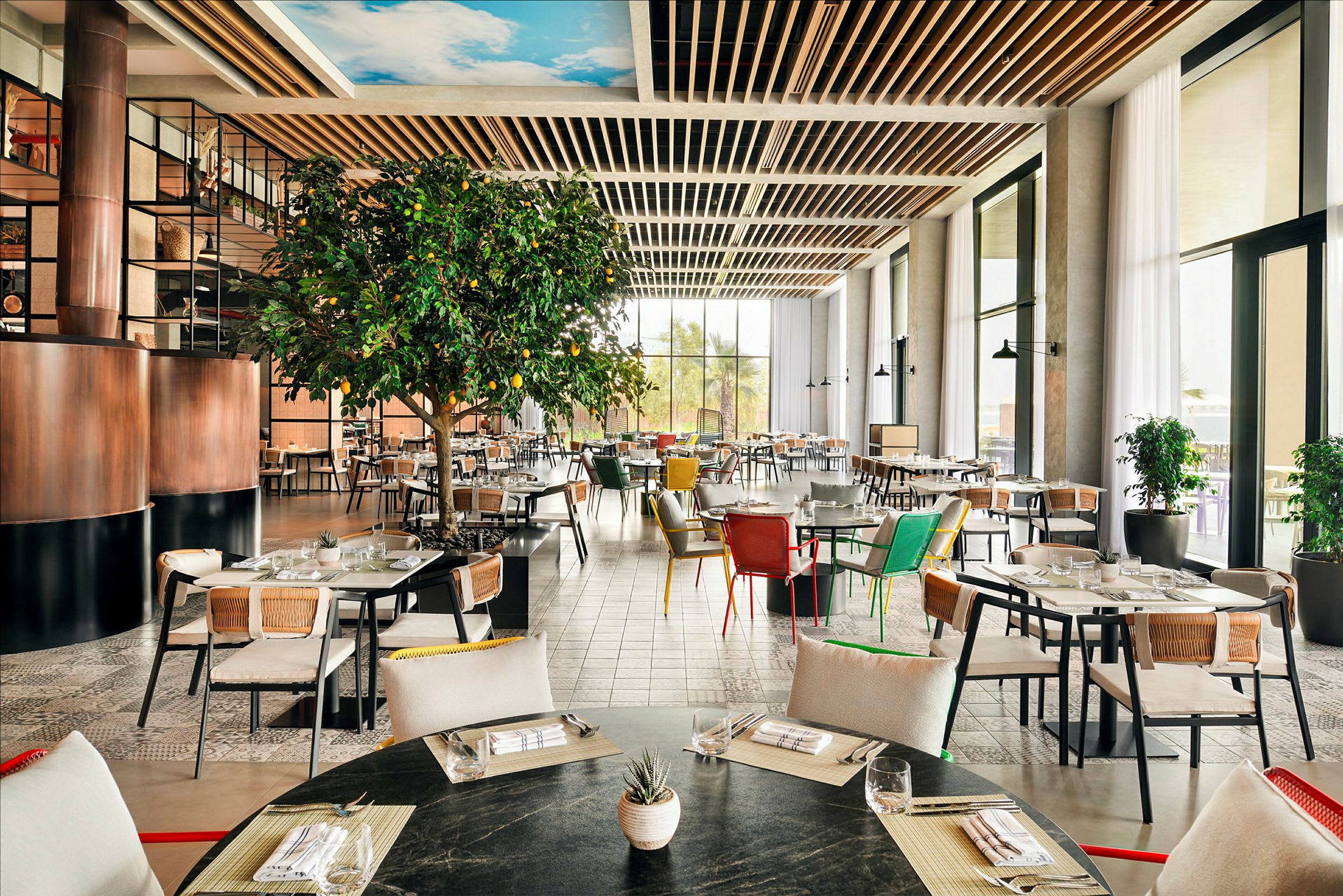 En lys og romslig restaurant med moderne møbler og et stort, frodig sitrontre. (AI-generert tekst)