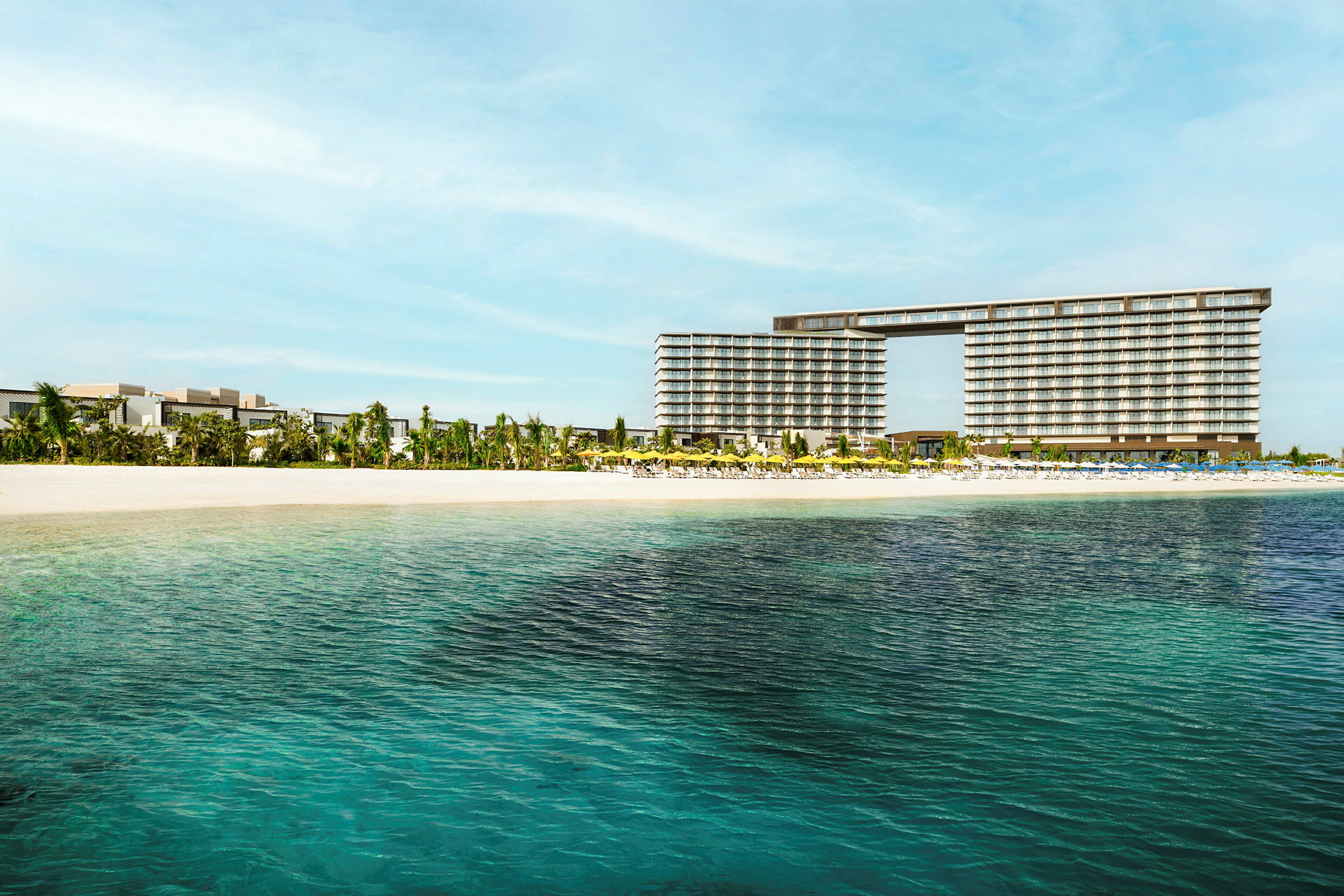 Utsikt over et hotell nær en sandstrand med klart vann. (AI-generert tekst)