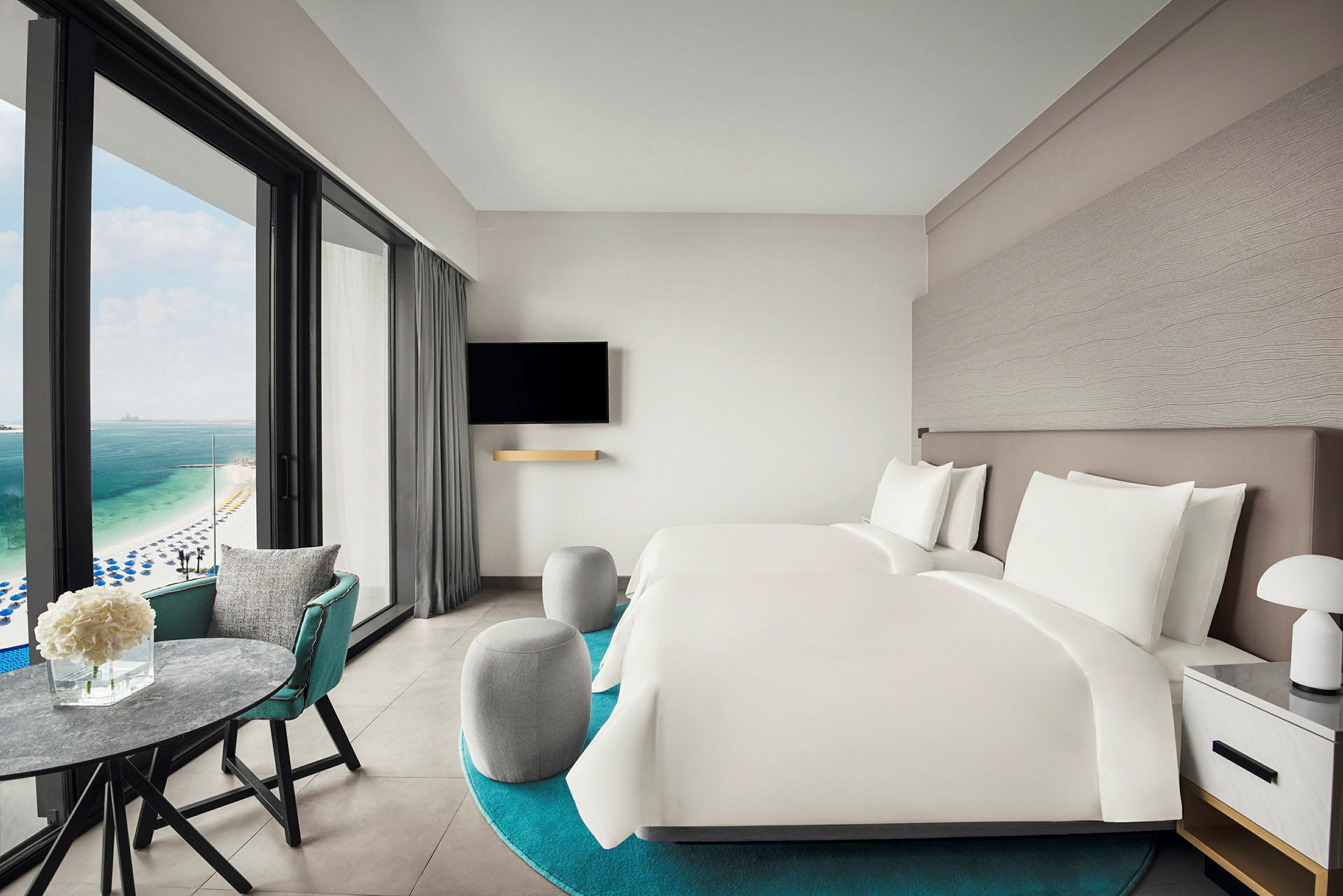 Hotellrom med to senger og utsikt over havet. (AI-generert tekst)