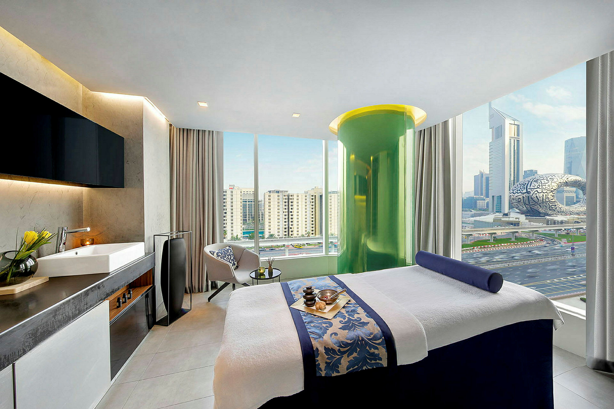 Rom med massasjebenk, store vinduer med utsikt over Dubai. Innredning i moderne stil. (AI-generert tekst)