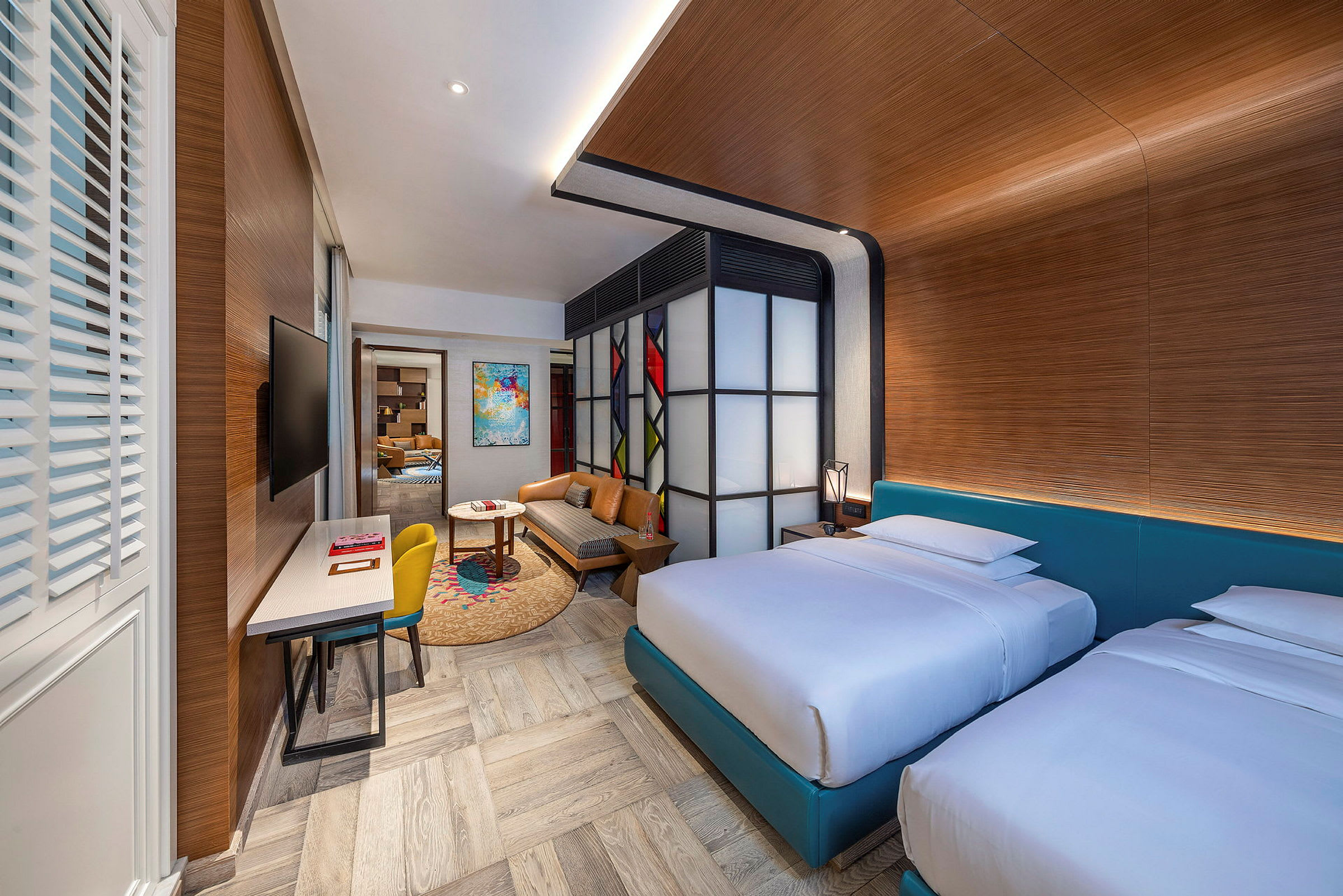 Et moderne hotellrom med to senger, en sittegruppe og et skrivebord. (AI-generert tekst)