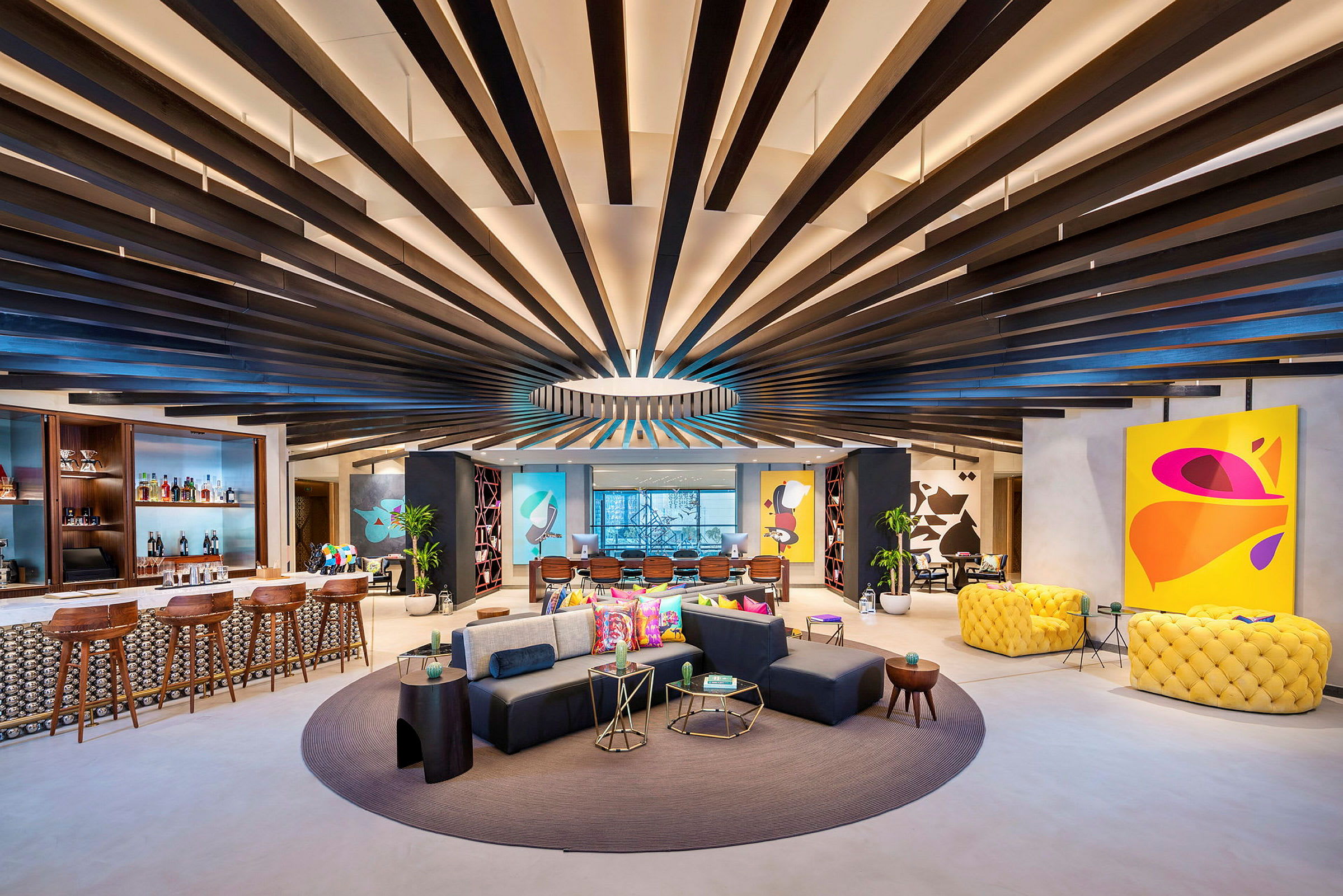 Moderne og fargerike møbler i en romslig lounge med et designet tak og kunst på veggene. (AI-generert tekst)