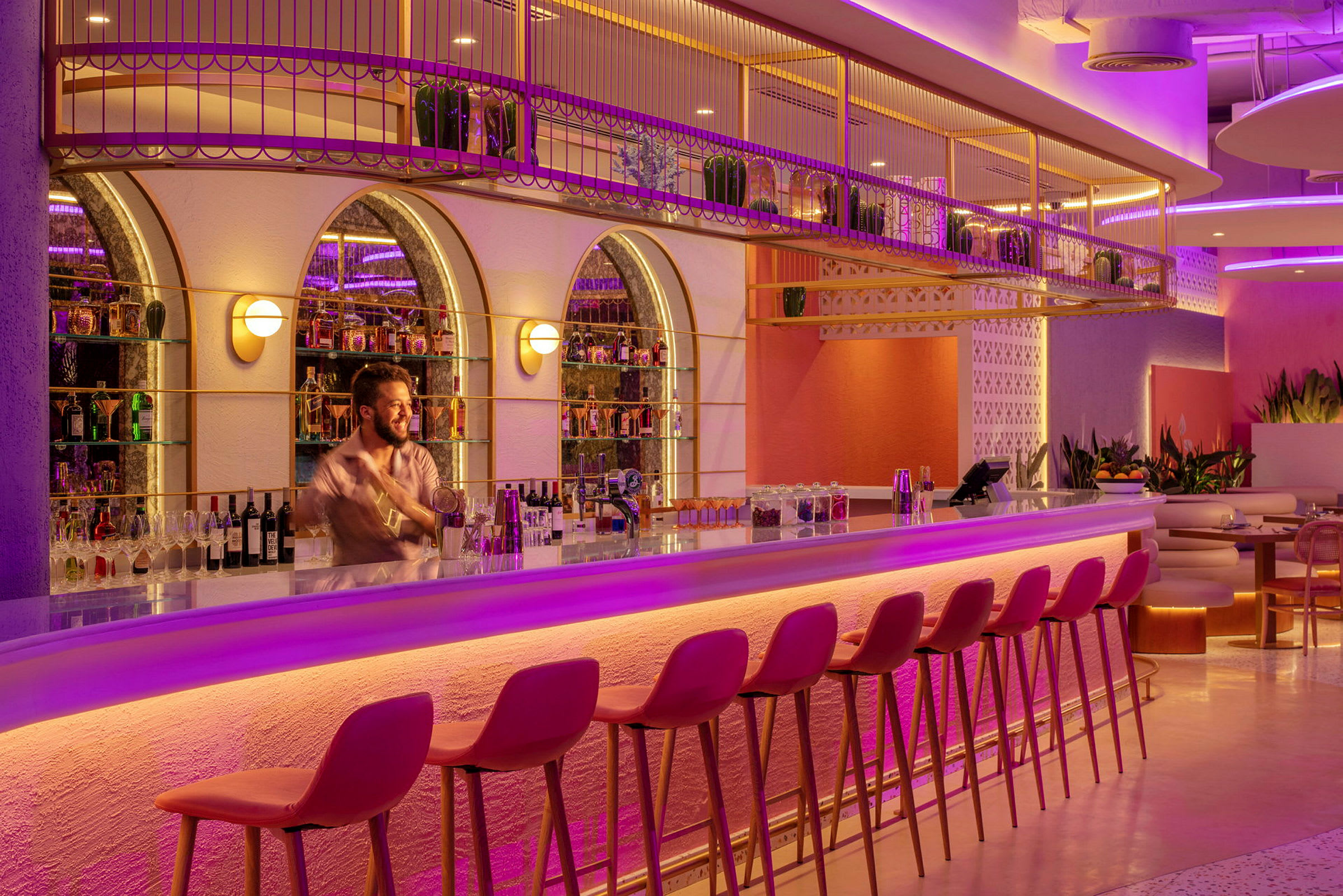 En elegant bar med rosa og lilla belysning, høye stoler og flasker på hyller. (AI-generert tekst)