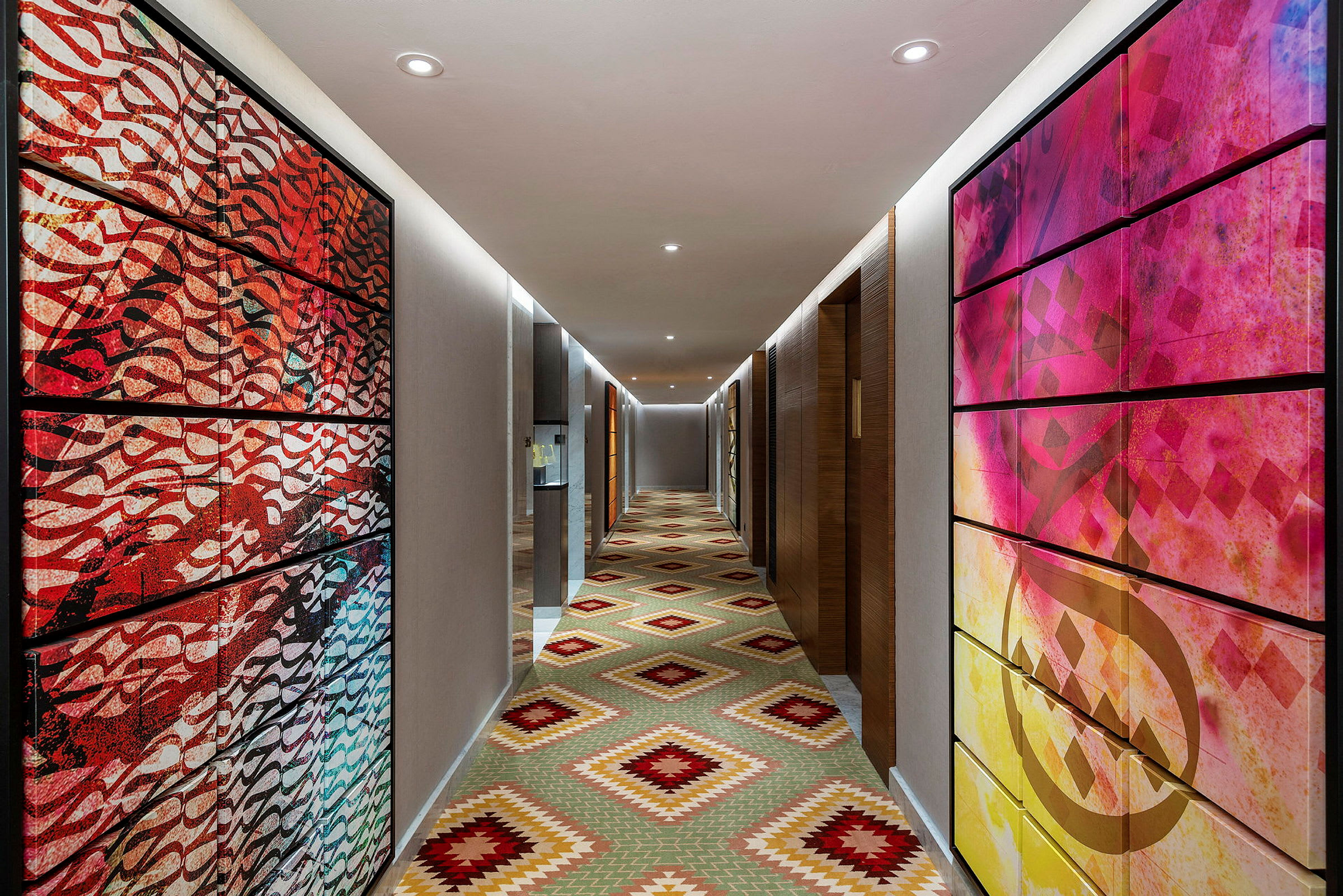 Hotellkorridor med fargerik kunst på veggene og et geometrisk mønstret gulv. (AI-generert tekst)