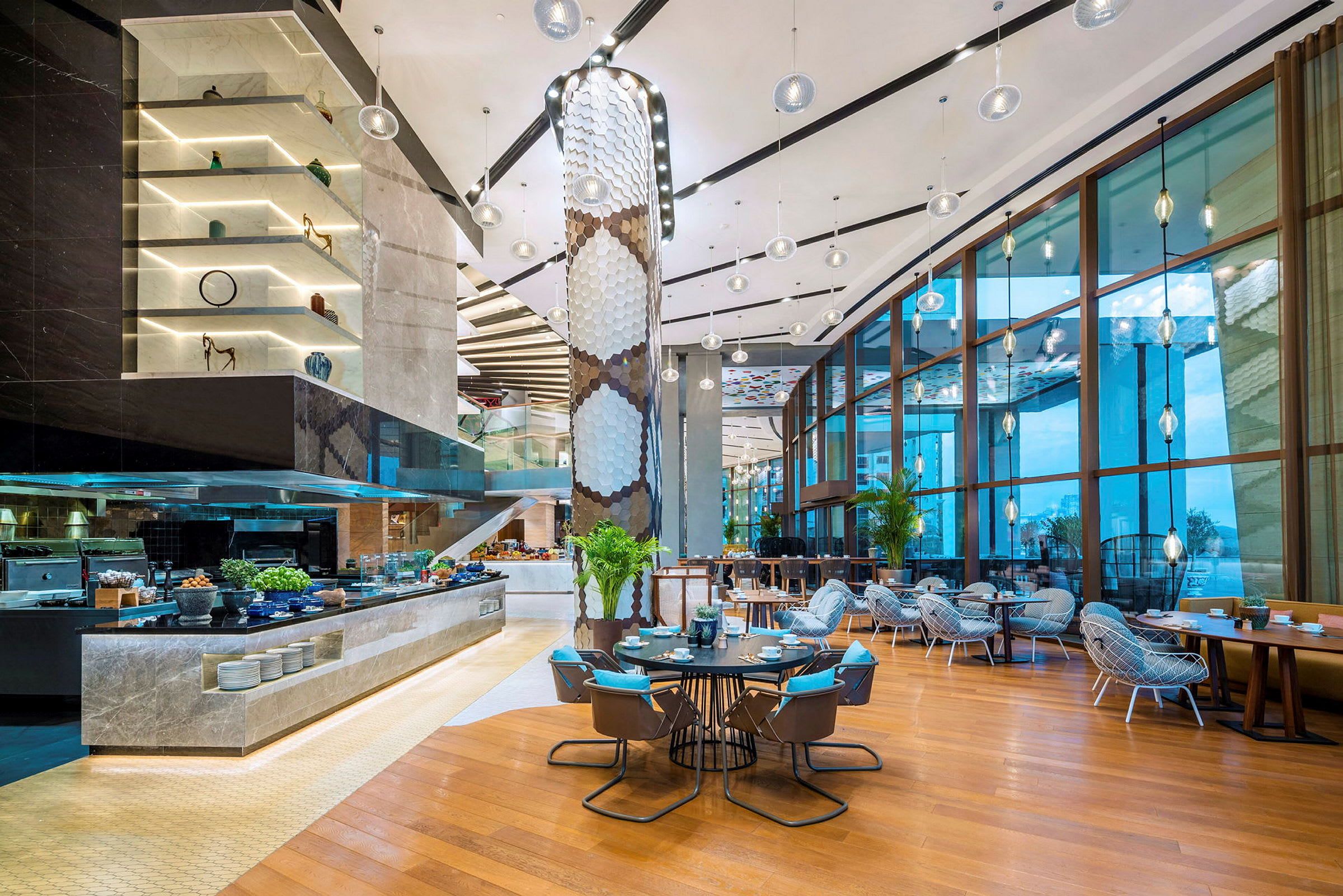 Moderne restaurantinteriør med store glassvinduer, trebord og stoler, samt et buffetområde med mat og dekorasjoner. (AI-generert tekst)