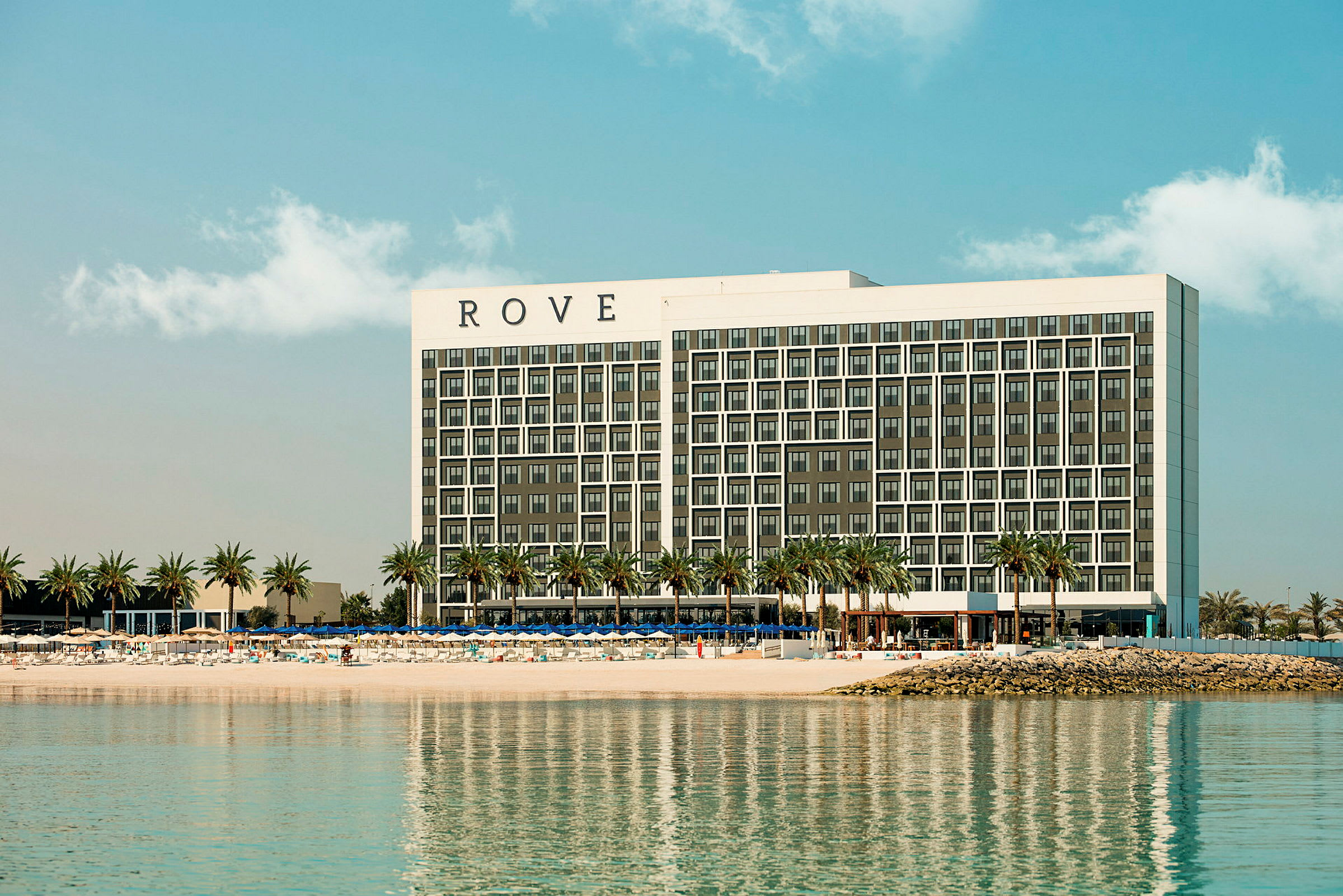Et hotell ved en strand med palmer. (AI-generert tekst)