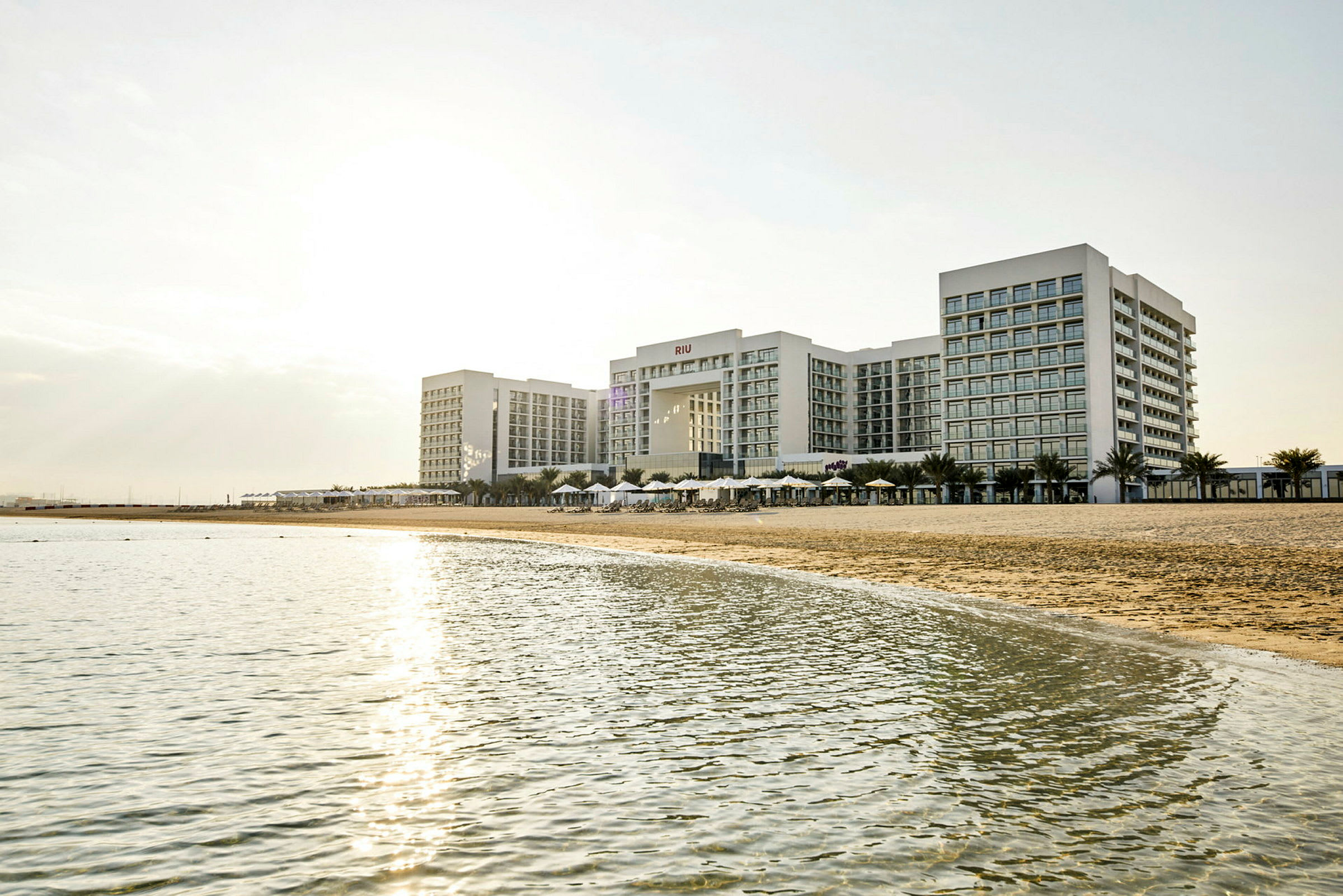Et stort hotellkompleks ved en strand med hav i forgrunnen. (AI-generert tekst)