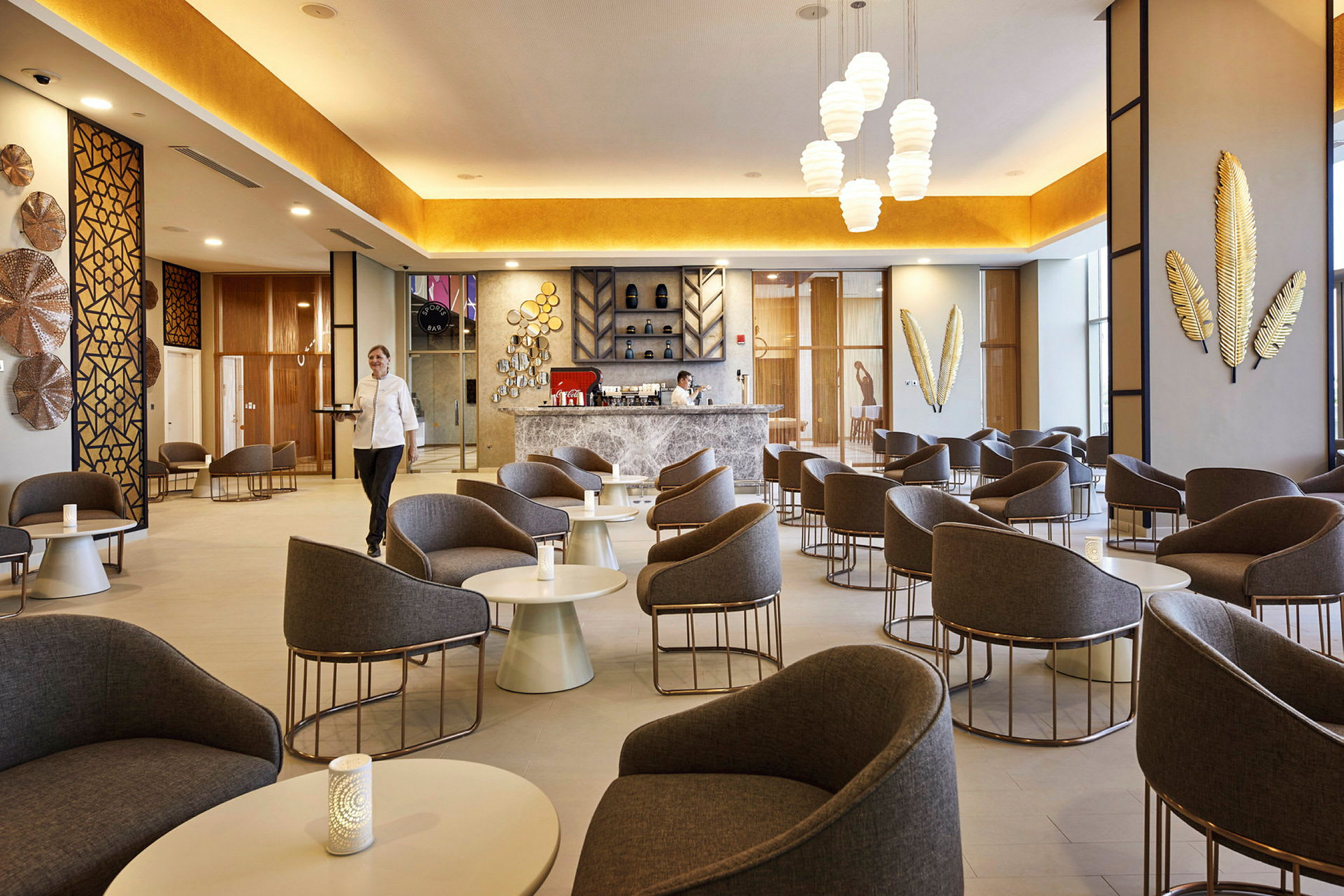 En moderne kafé/lounge med komfortable lenestoler og bord, dekorative veggdetaljer og en innbydende bardisk. (AI-generert tekst)