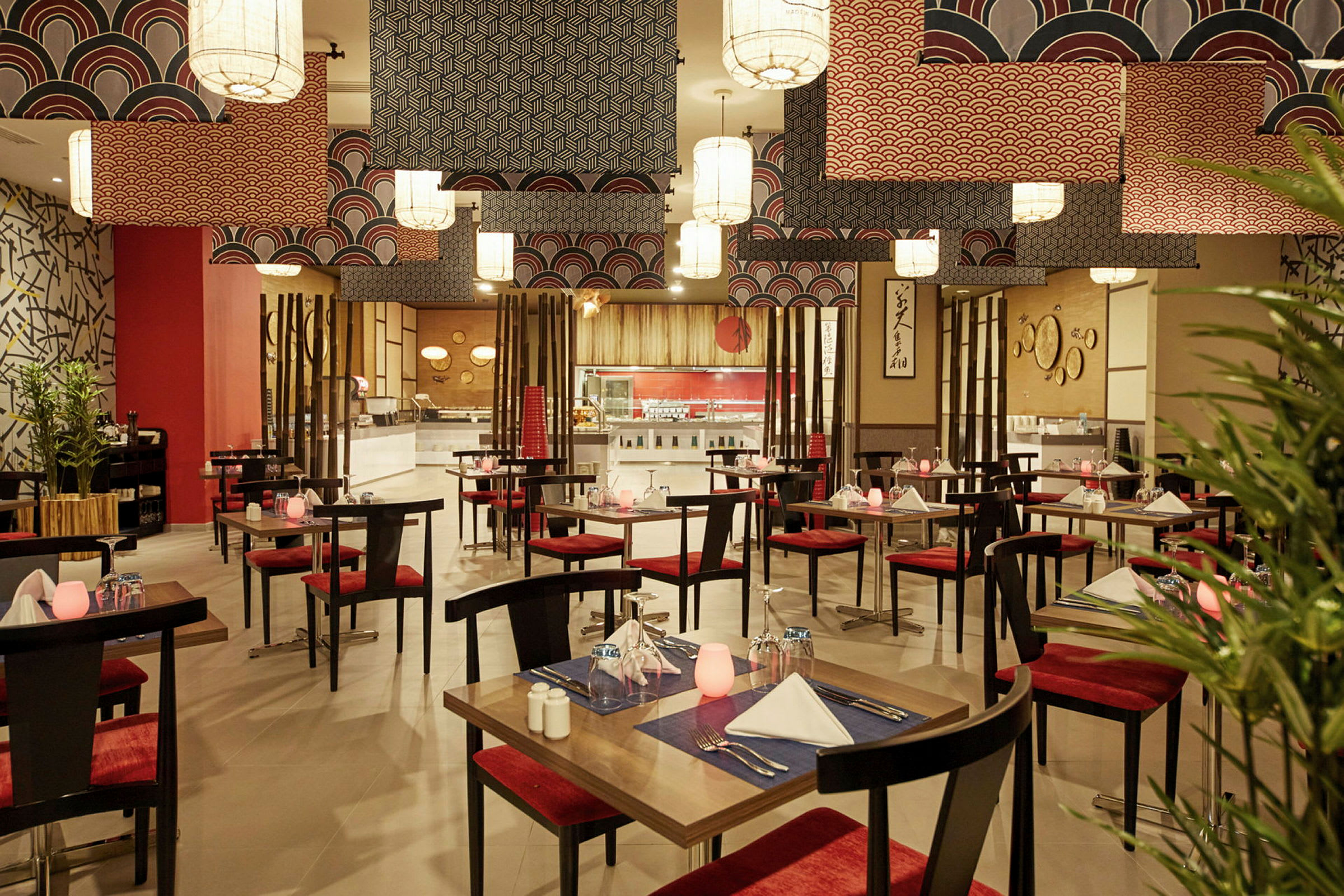 En restaurant med bord og røde stoler, dekorert med orientalske motiver og moderne taklamper. (AI-generert tekst)